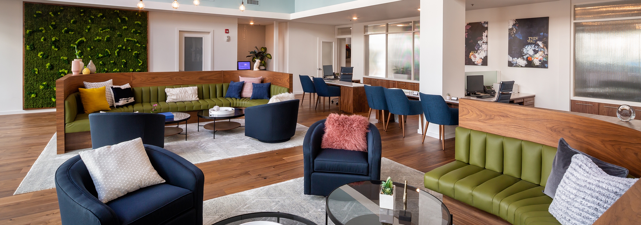 AMLI South Shore leasing office with dark hardwood and navy blue and olive green seating with white floor rug and light walls
