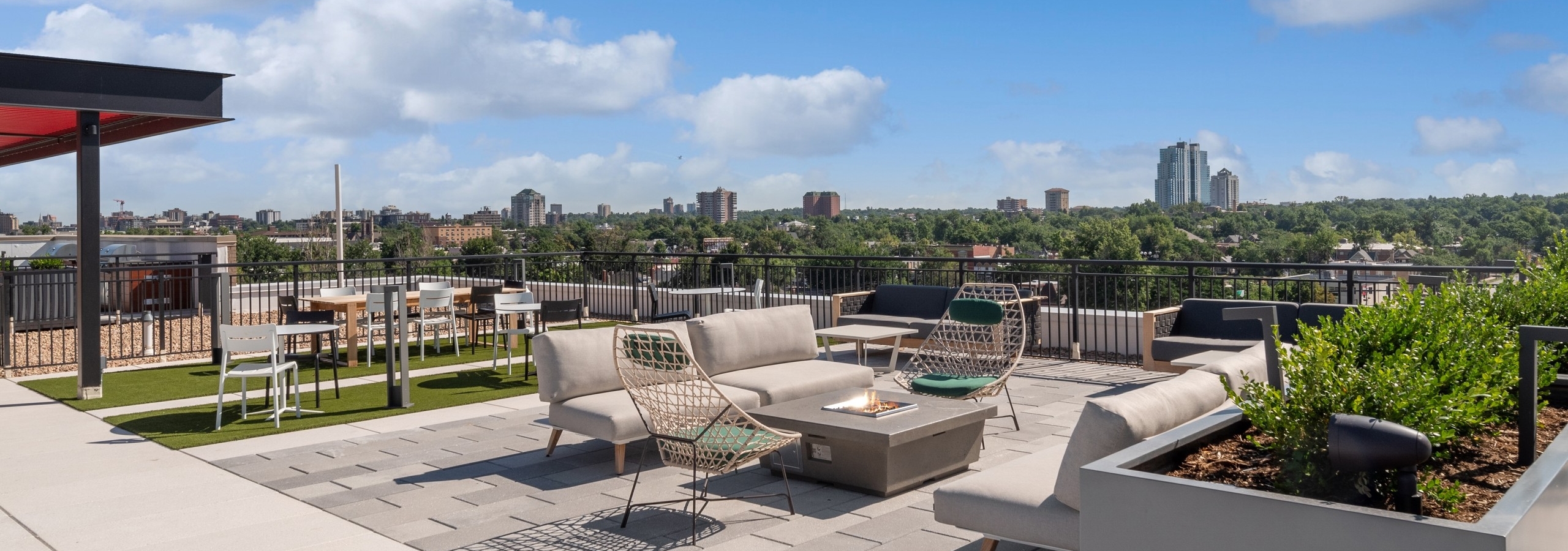 Rooftop seating area with firepit at AMLI Broadway Park with  tables and chairs surrounded by city skyline view
