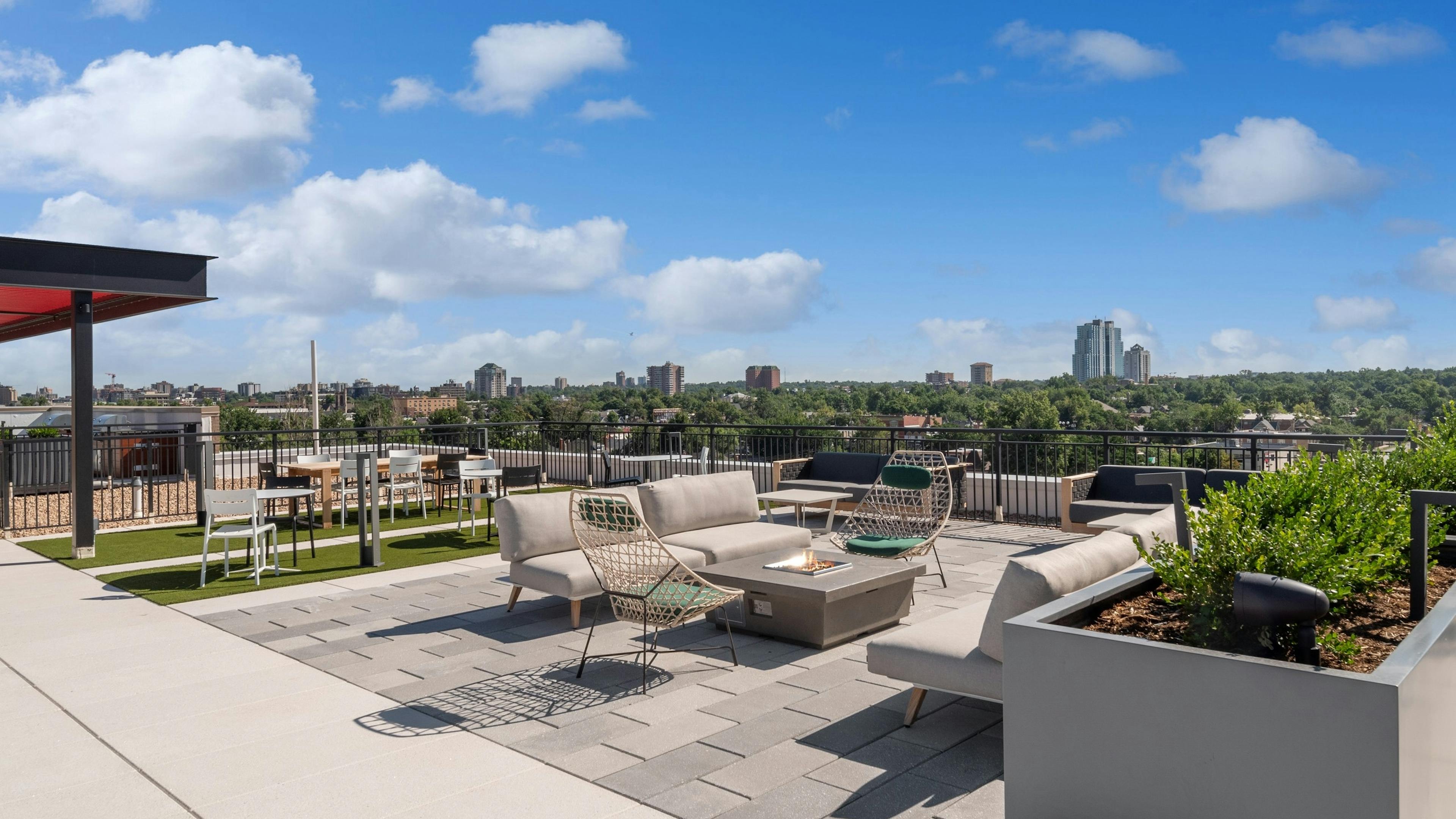 Rooftop seating area with firepit at AMLI Broadway Park with  tables and chairs surrounded by city skyline view