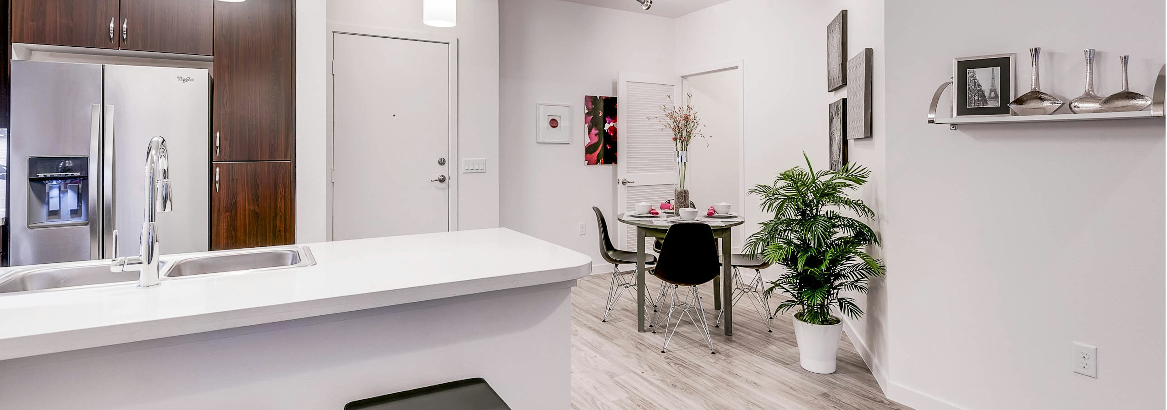 A view of a kitchen and dining room at AMLI Cherry Creek apartment with white walls and a small dining table and a fridge