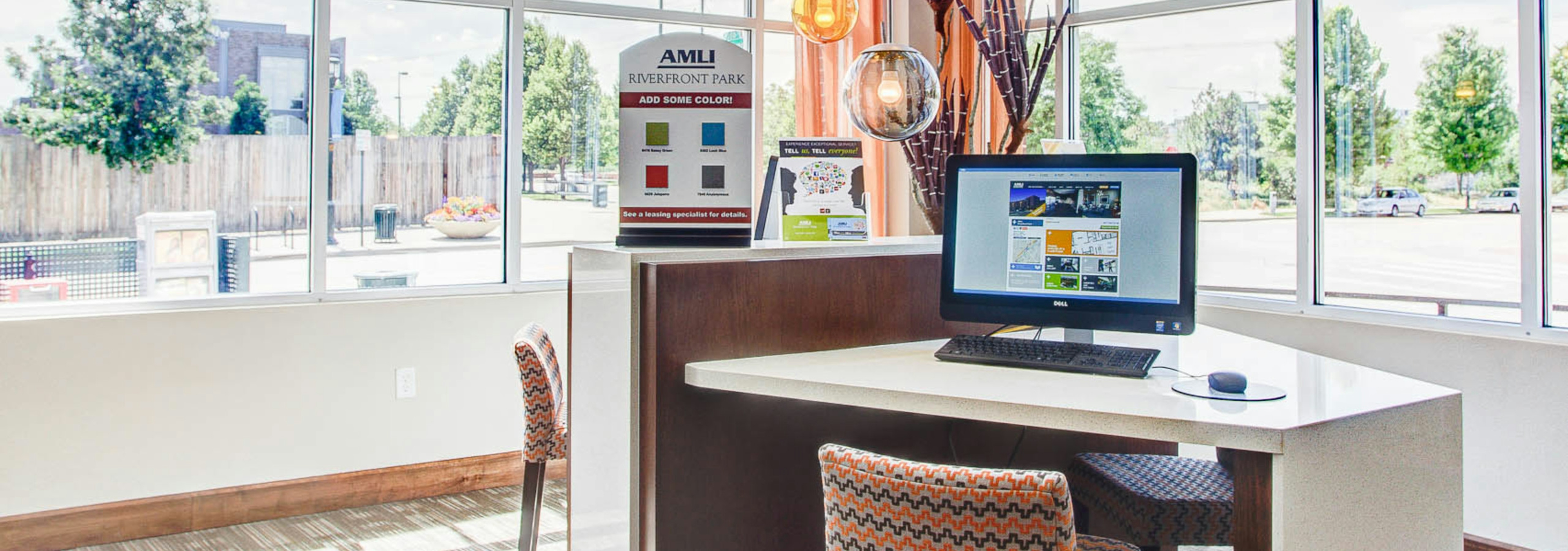 Interior photo of the leasing office at AMLI Riverfront Park featuring a desk with a computer and window views to the street