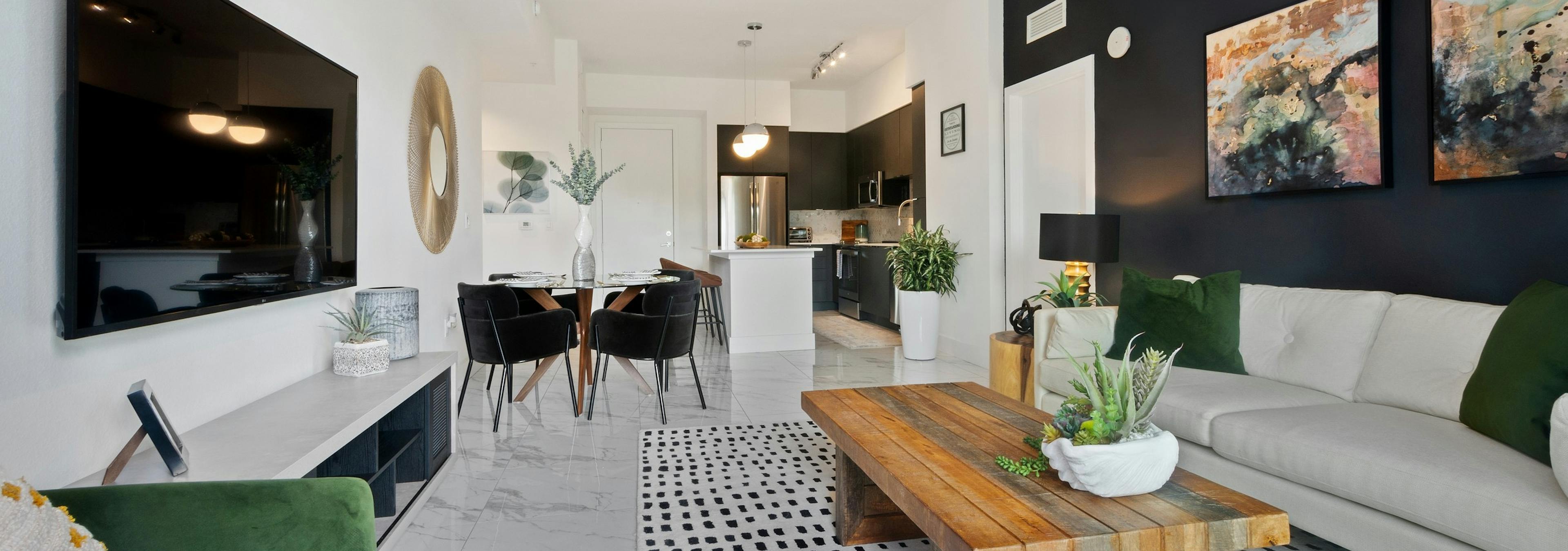 AMLI Park West apartments living area with white sofa and green accent pillows and coffee table and a view into the kitchen 