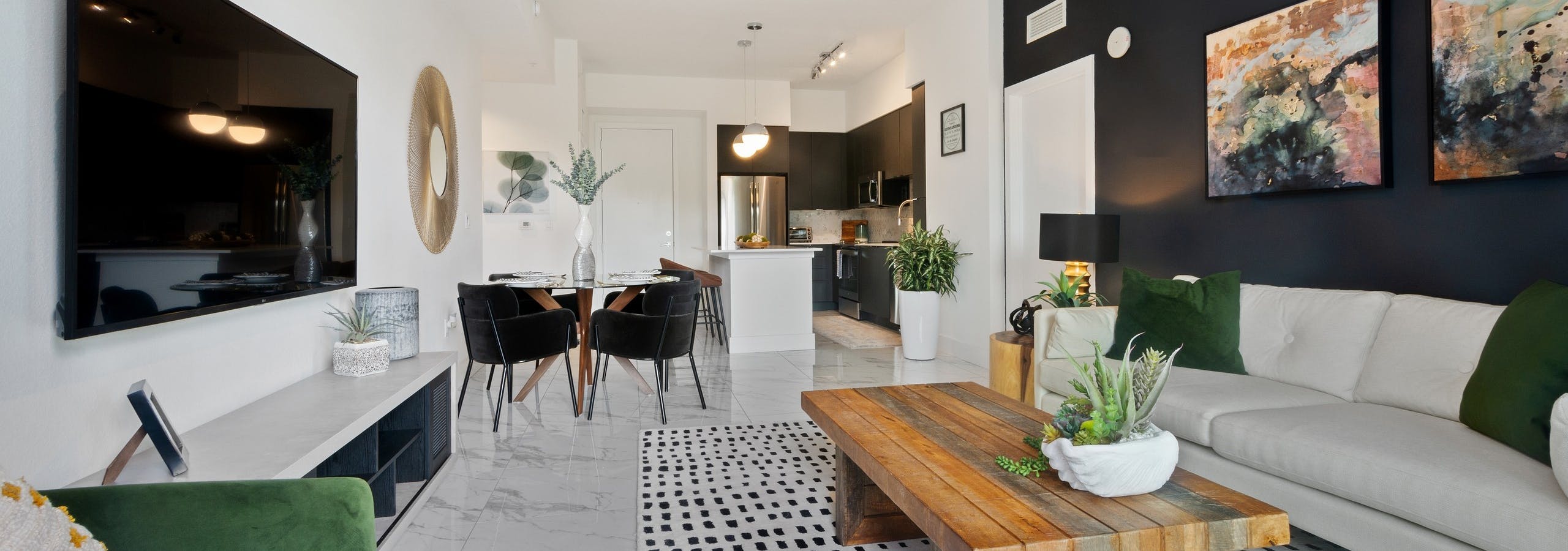 AMLI Park West apartments living area with white sofa and green accent pillows and coffee table and a view into the kitchen