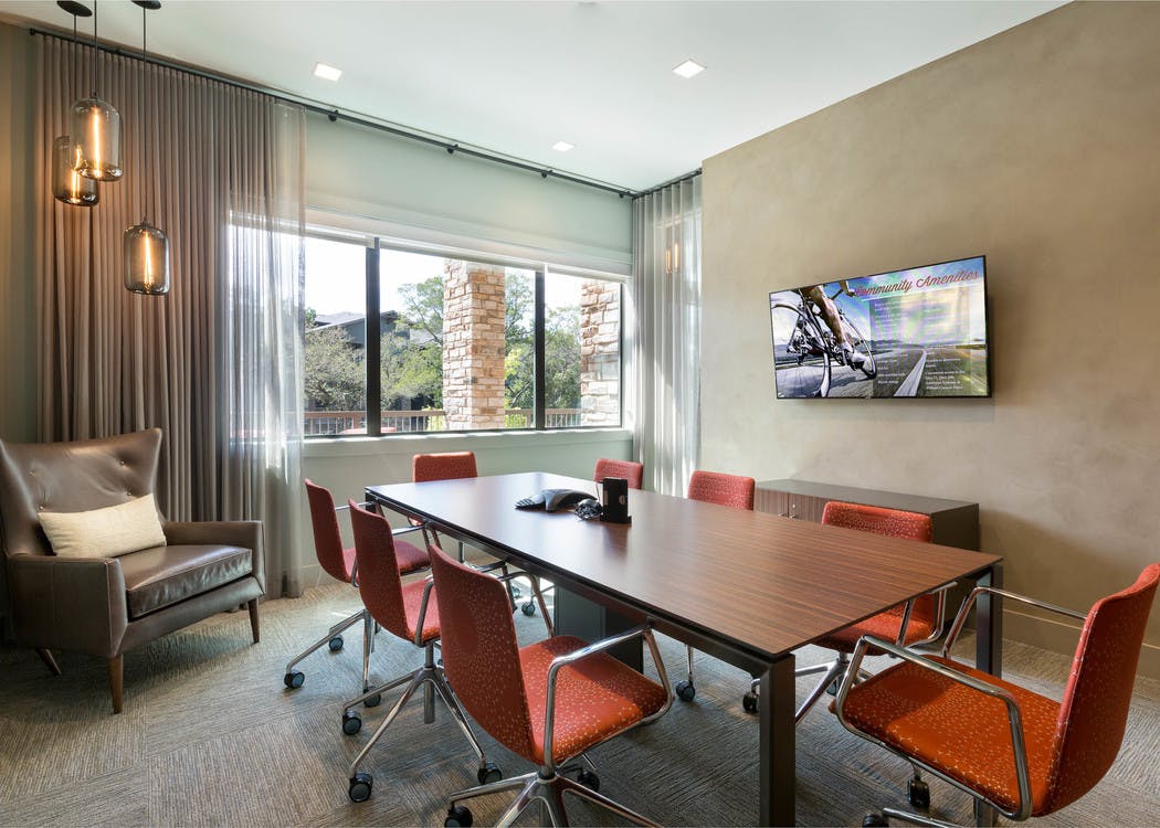 Interior view of AMLI Covered Bridge resident conference room with an eight-person table and a large screen monitor