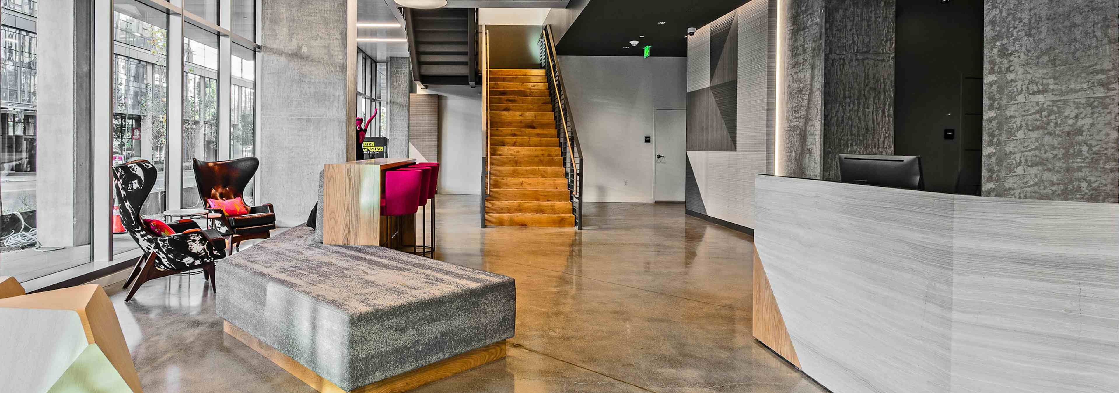 Interior lobby of AMLI Arc with seating floor to ceiling windows wooden stairs leading to leasing office and concierge desk 