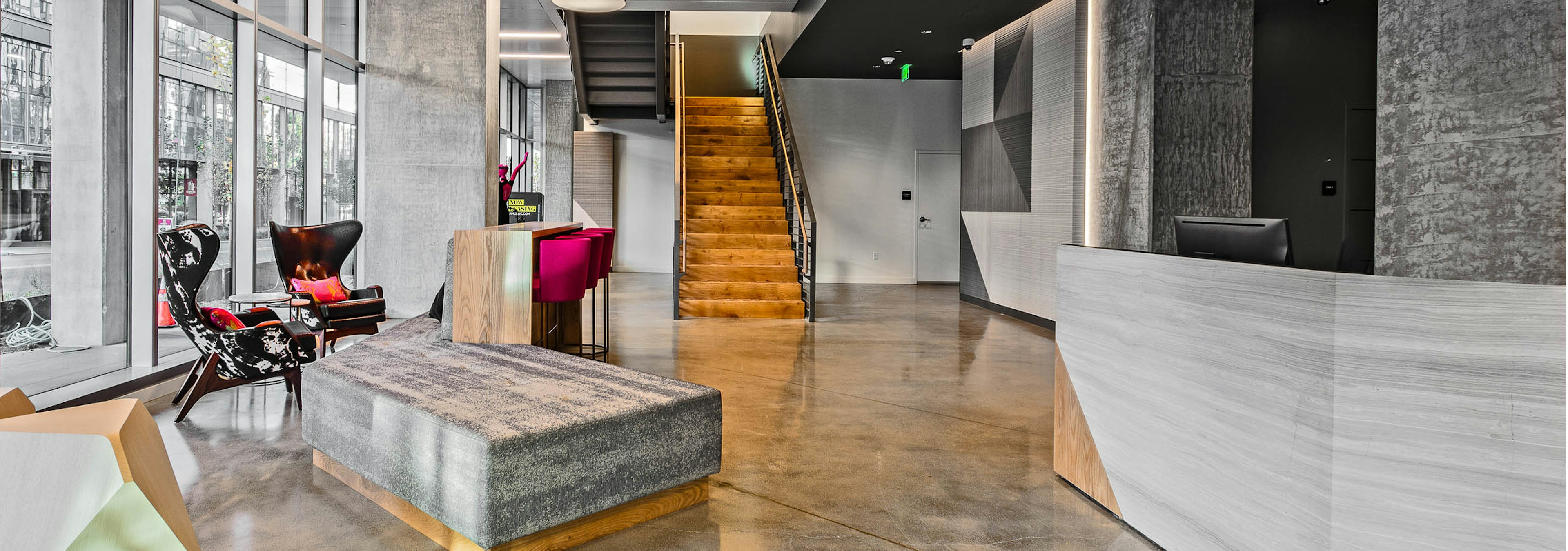 Interior lobby of AMLI Arc with seating floor to ceiling windows wooden stairs leading to leasing office and concierge desk 