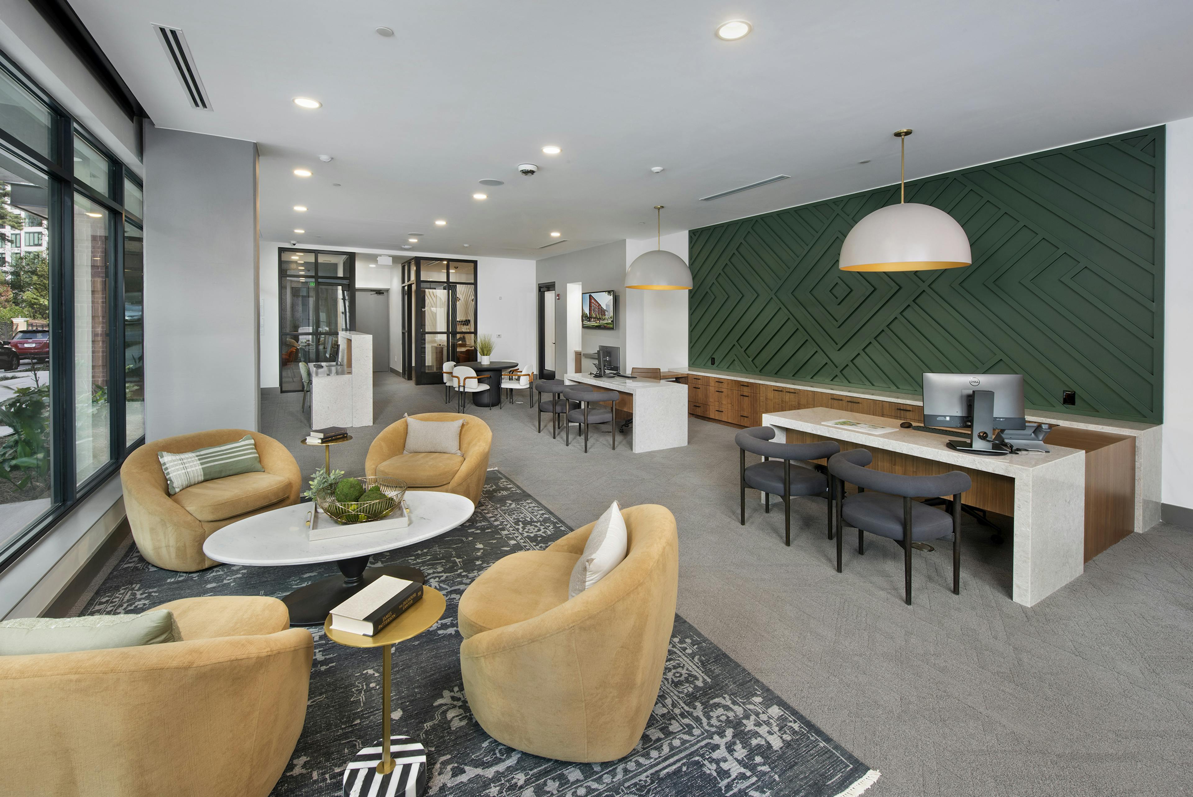 AMLI Flatiron leasing office with stuffed yellow chairs and coffee white table and white desks with grey chairs by dark green wall