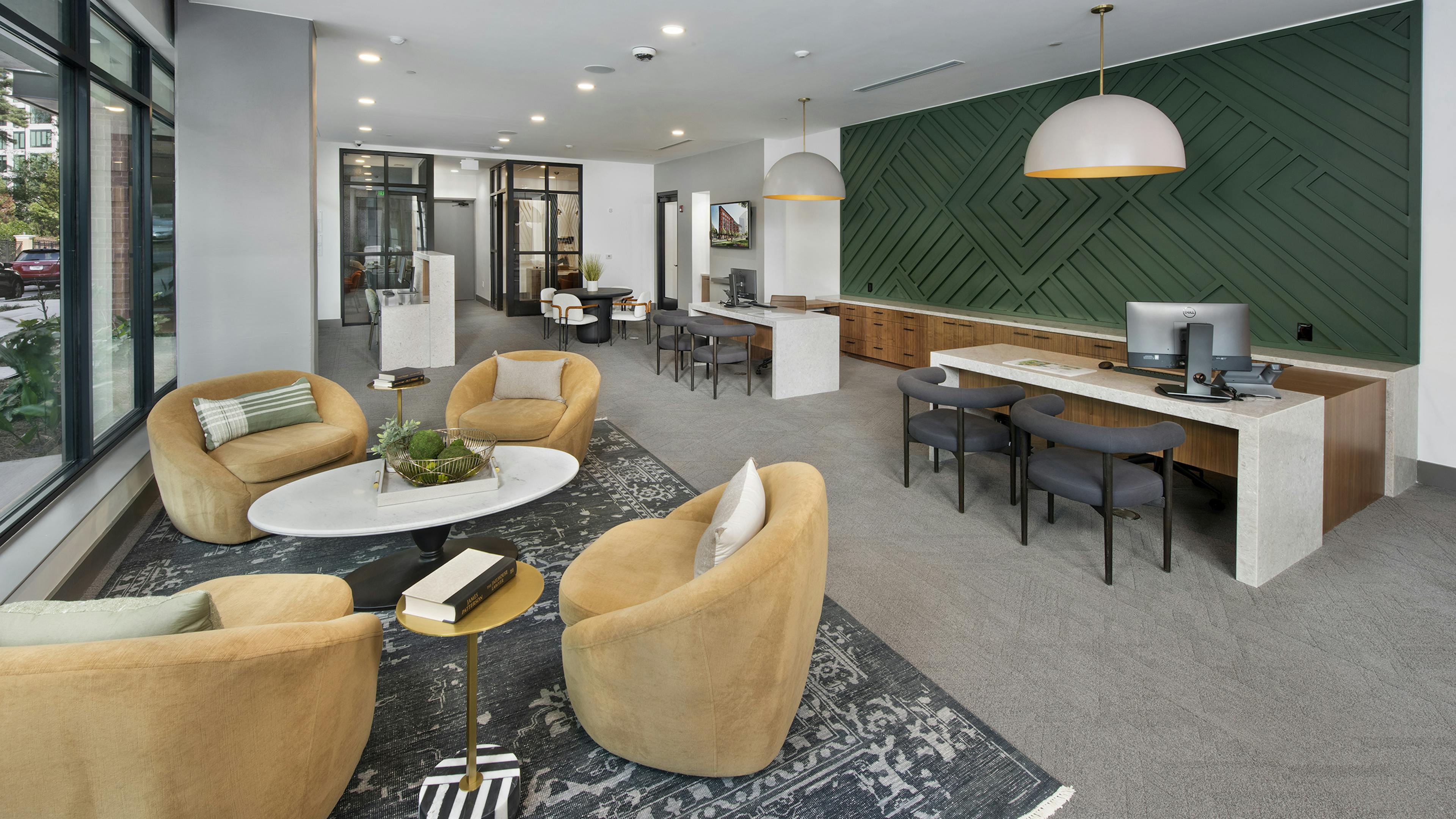 AMLI Flatiron leasing office with stuffed yellow chairs and coffee white table and white desks with grey chairs by dark green wall