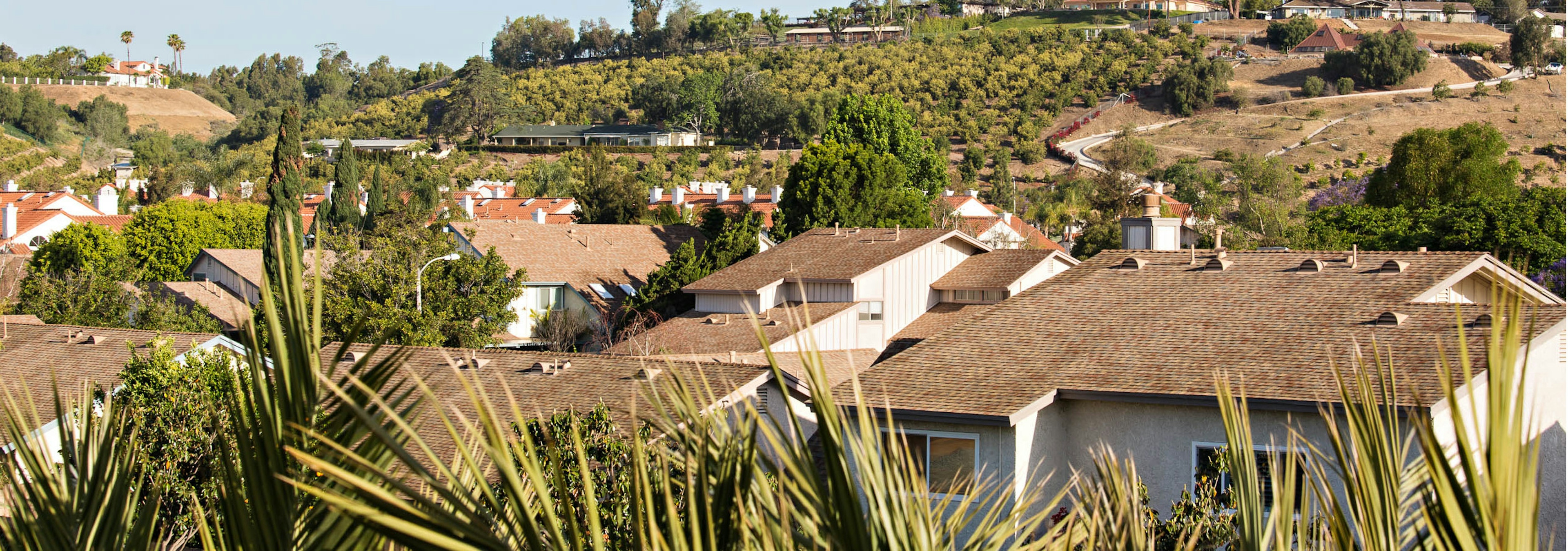 Daytime aerial view above AMLI Spanish Hills apartment community capturing the outside hills and lush greenery of Camarillo