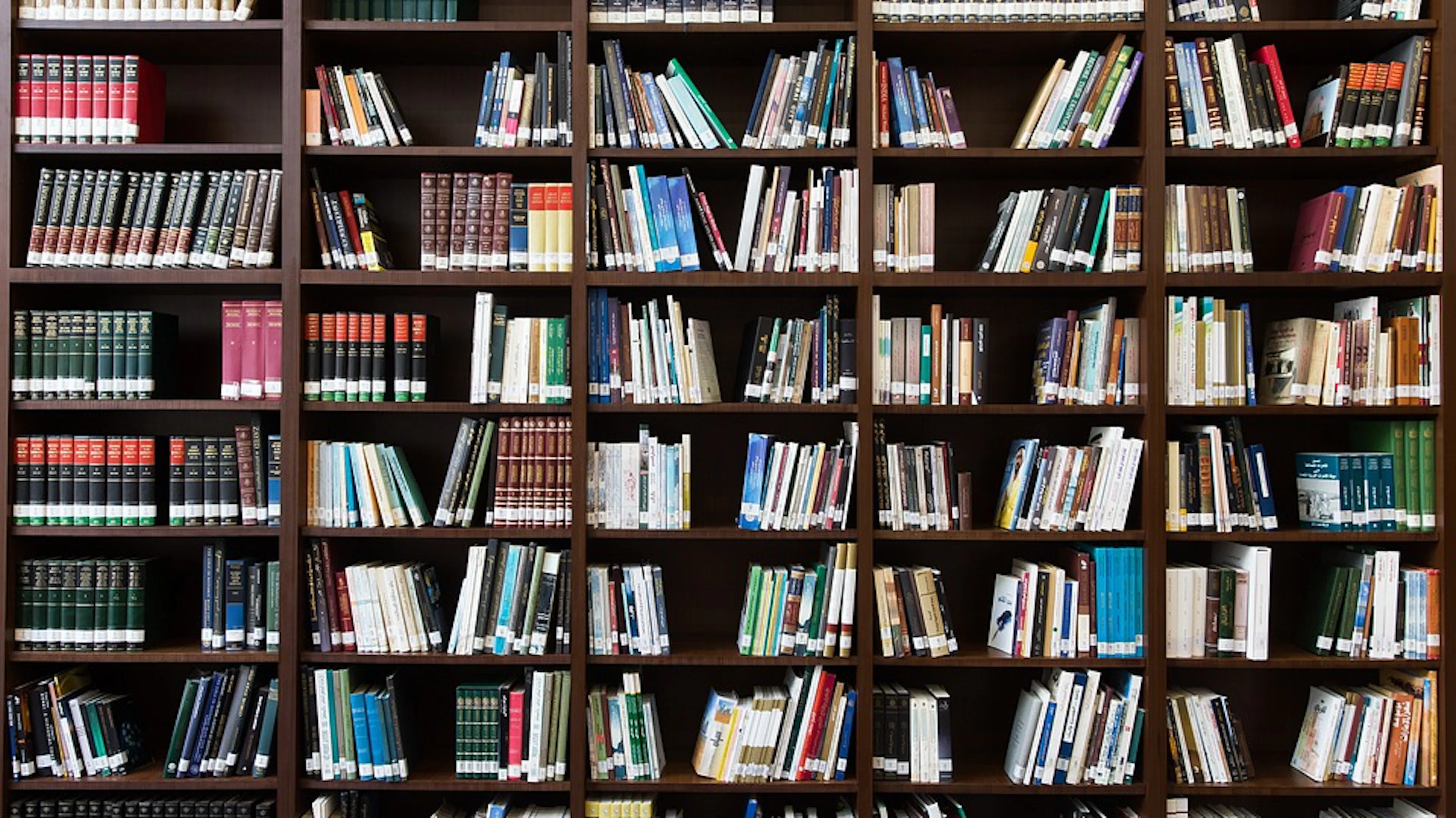 A large dark wooden bookshelf with a large collection of old library books