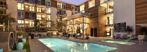 Evening view of AMLI Marina Del Rey landscaped and lit swimming pool area with lounge seating, jacuzzi and entertaining lanai