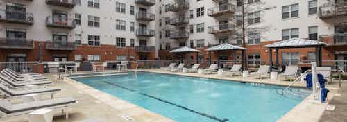 AMLI Downtown courtyard resort style pool surrounded by gray lounge chairs with small white tables and cabanas