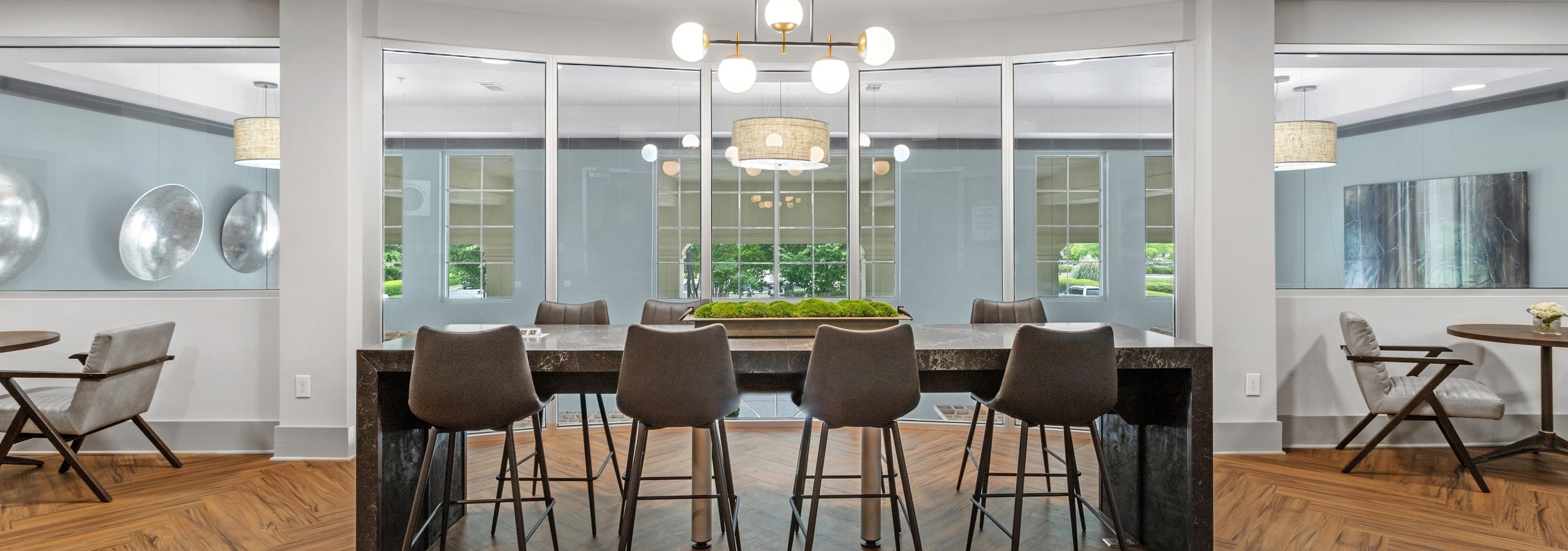 AMLI North Point business center with center island and stools and wood flooring with modern lighting and front window view