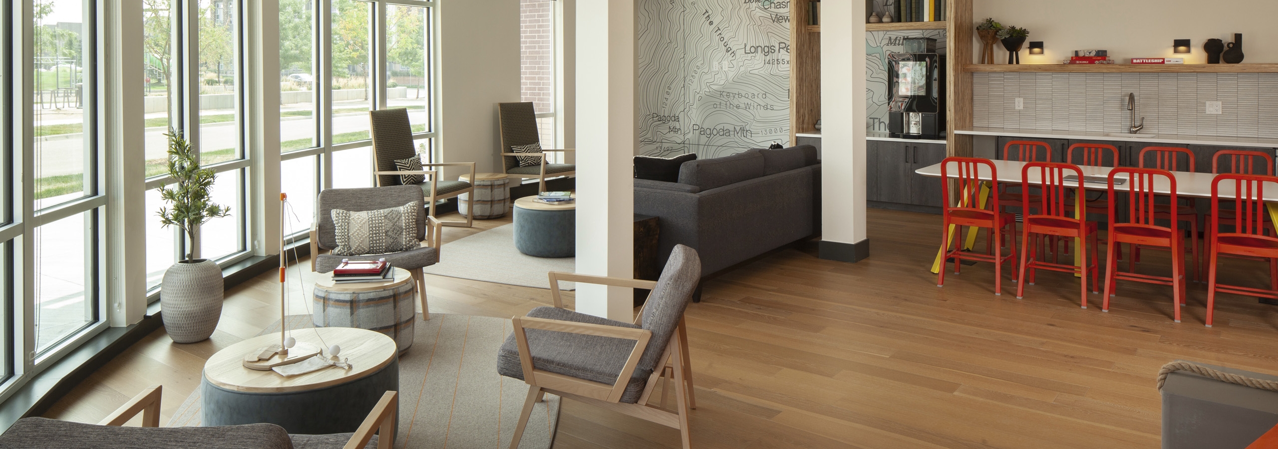 AMLI Littleton Village cyber café with 12 hanging lights and 2 seating areas by large windows and table with orange chairs