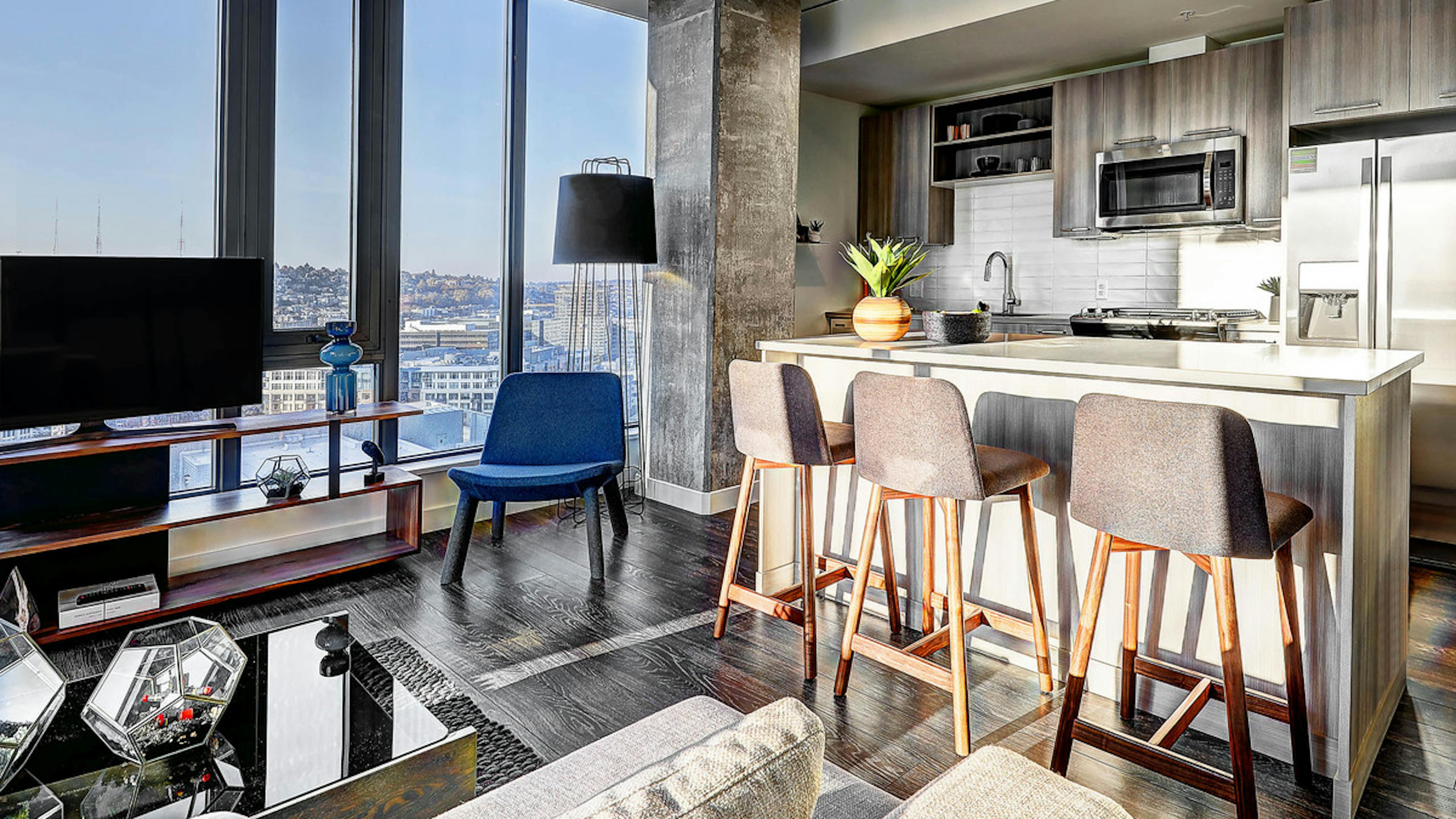 Interior apartment of AMLI Arc with light colored island and kitchen with stainless steel appliances and living room with big floor to ceiling windows   