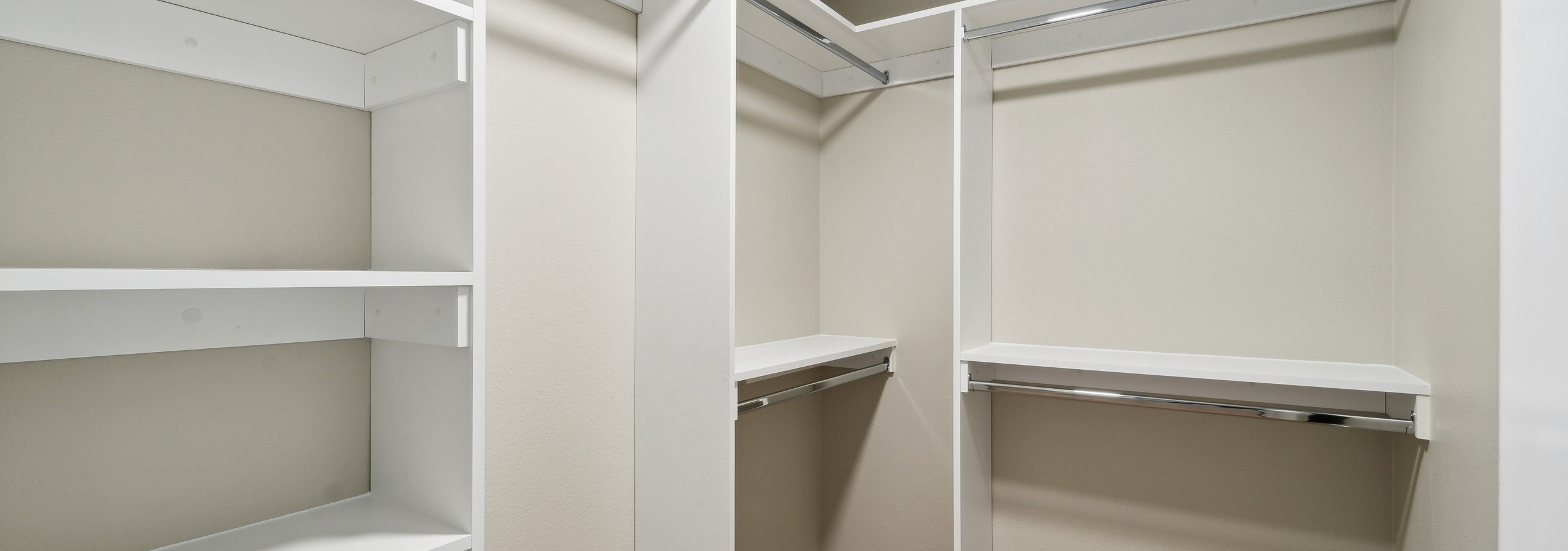 Walk in closet with California closet system at AMLI 535 apartments with white shelves and silver rods and beige walls