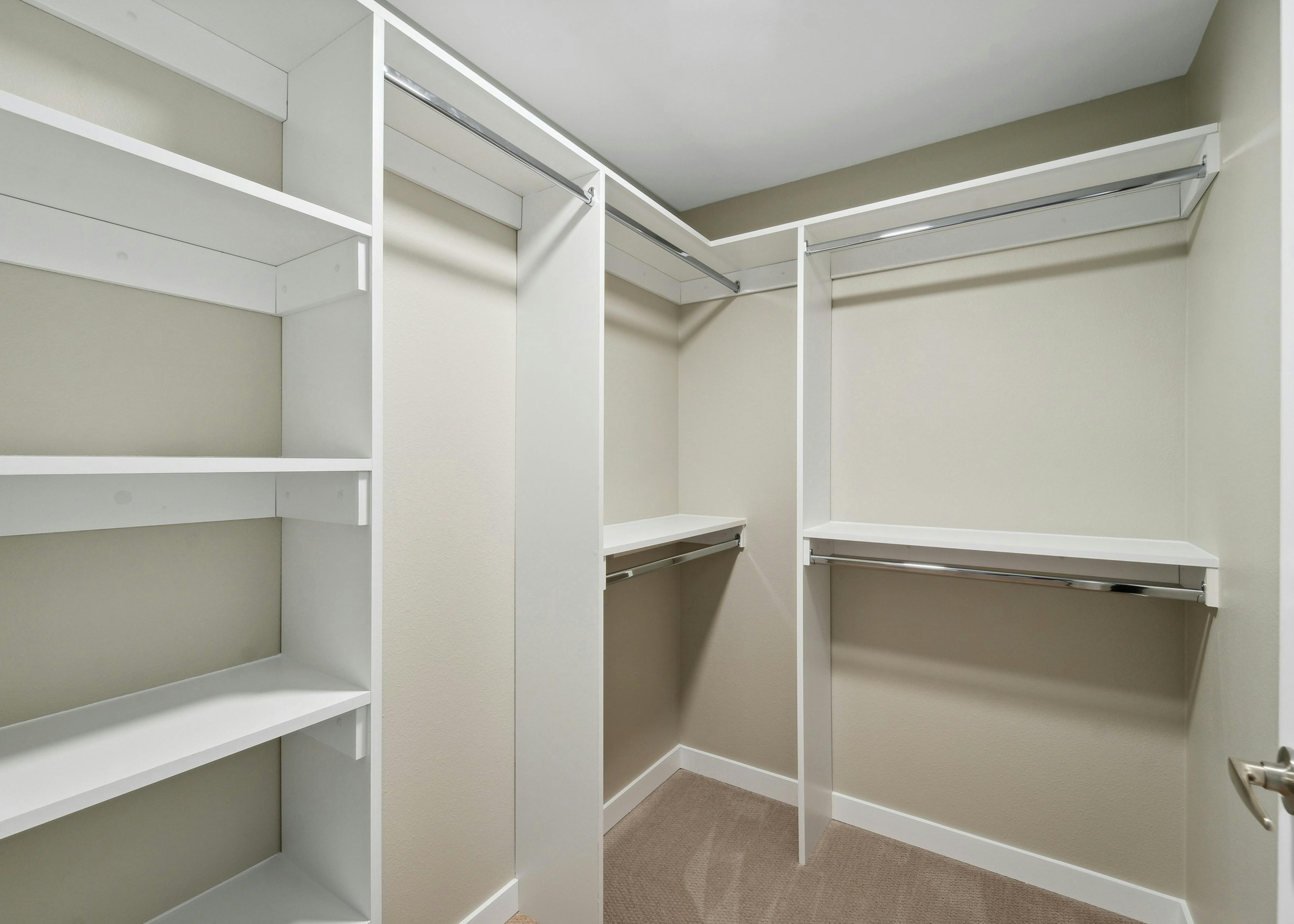 Walk in closet with California closet system at AMLI 535 apartments with white shelves and silver rods and beige walls