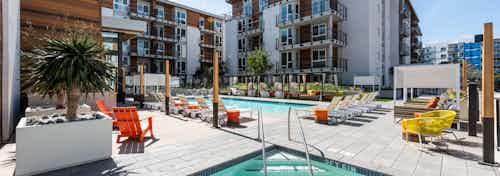 Daytime view of AMLI Marina Del Rey swimming pool area with varied style lounge seating, cabanas daybeds and lush landscaping