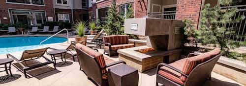 Exterior view of the outdoor fireplace at AMLI Park Avenue apartments with multiple seating areas and a view of the pool