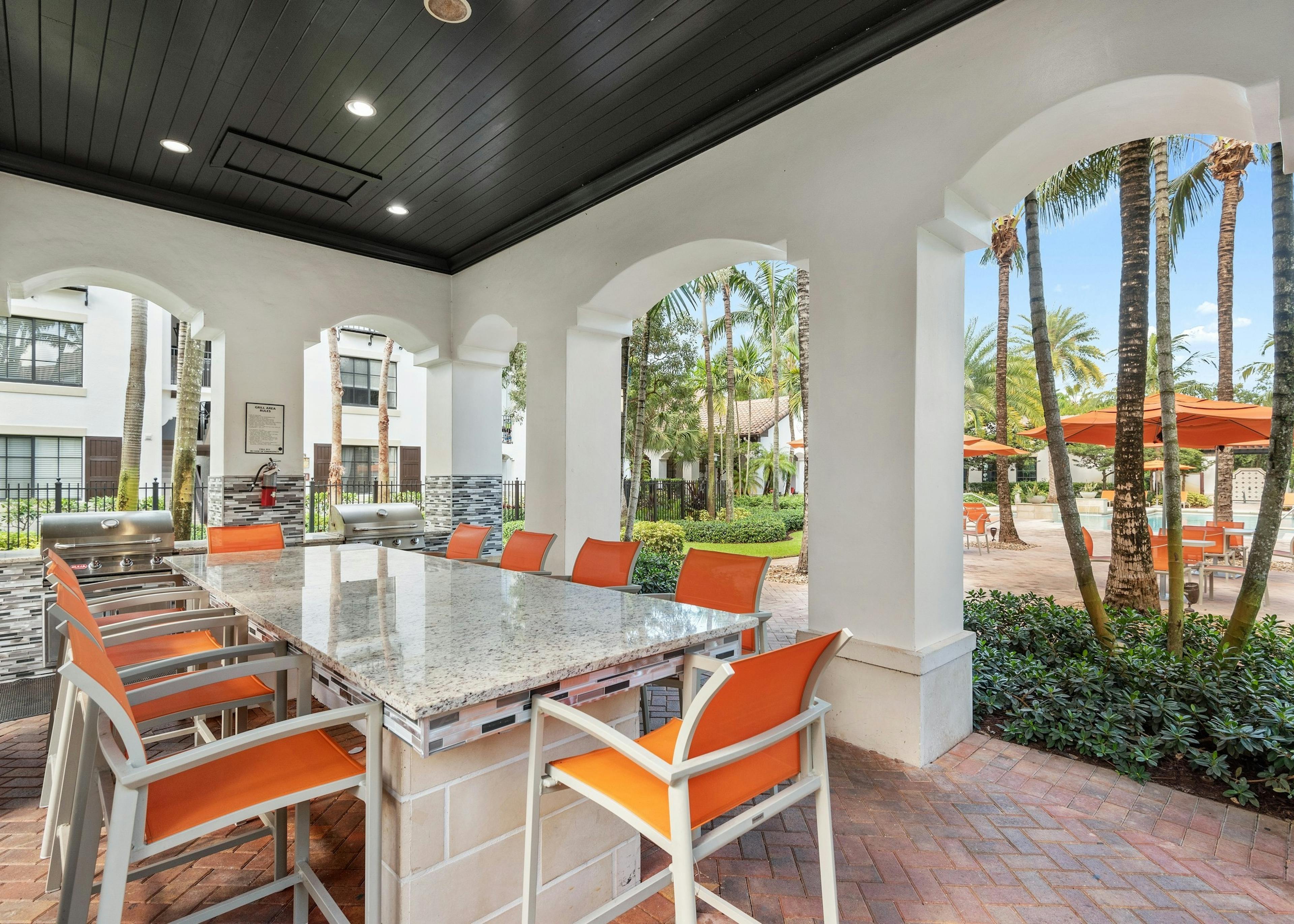 Daytime view of AMLI Toscana Place built in barbeque seating area with free standing island and high top seating
