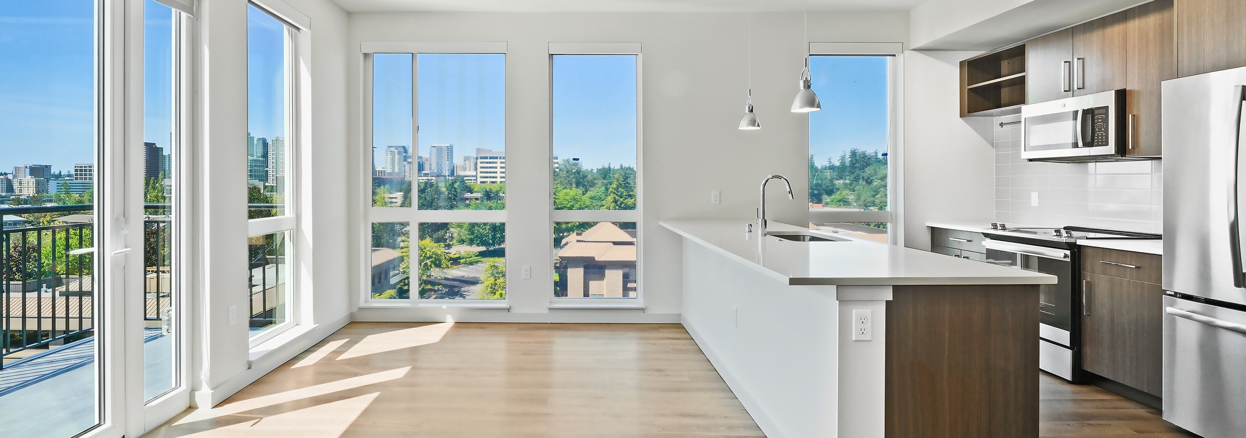 Interior of AMLI Spring District apartment kitchen with wood floors and floor to ceiling windows showing beautiful views