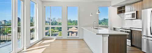 Interior of AMLI Spring District apartment kitchen with wood floors and floor to ceiling windows showing beautiful views