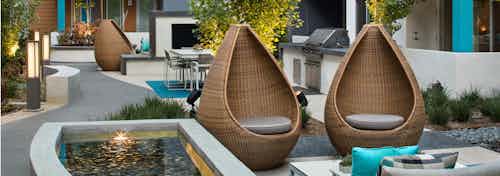 Daytime view of outdoor courtyard at AMLI Uptown Orange with teardrop wicker chairs and reflection ponds and grill stations
