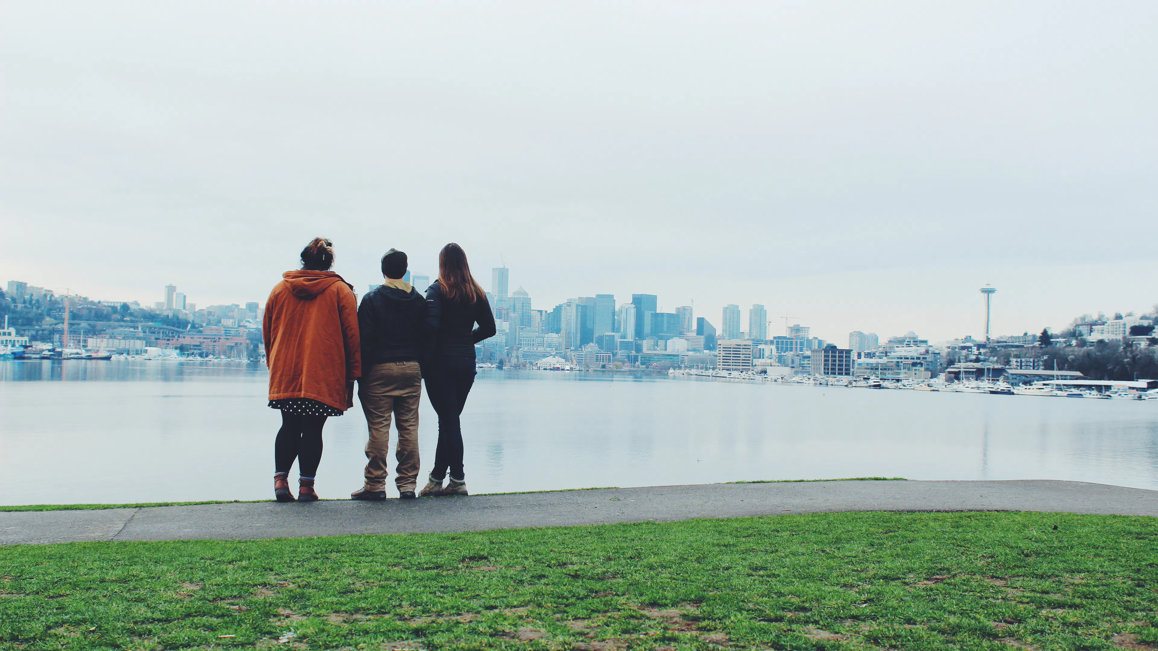 three friends facing away from the camera looking at Seattle across the lake