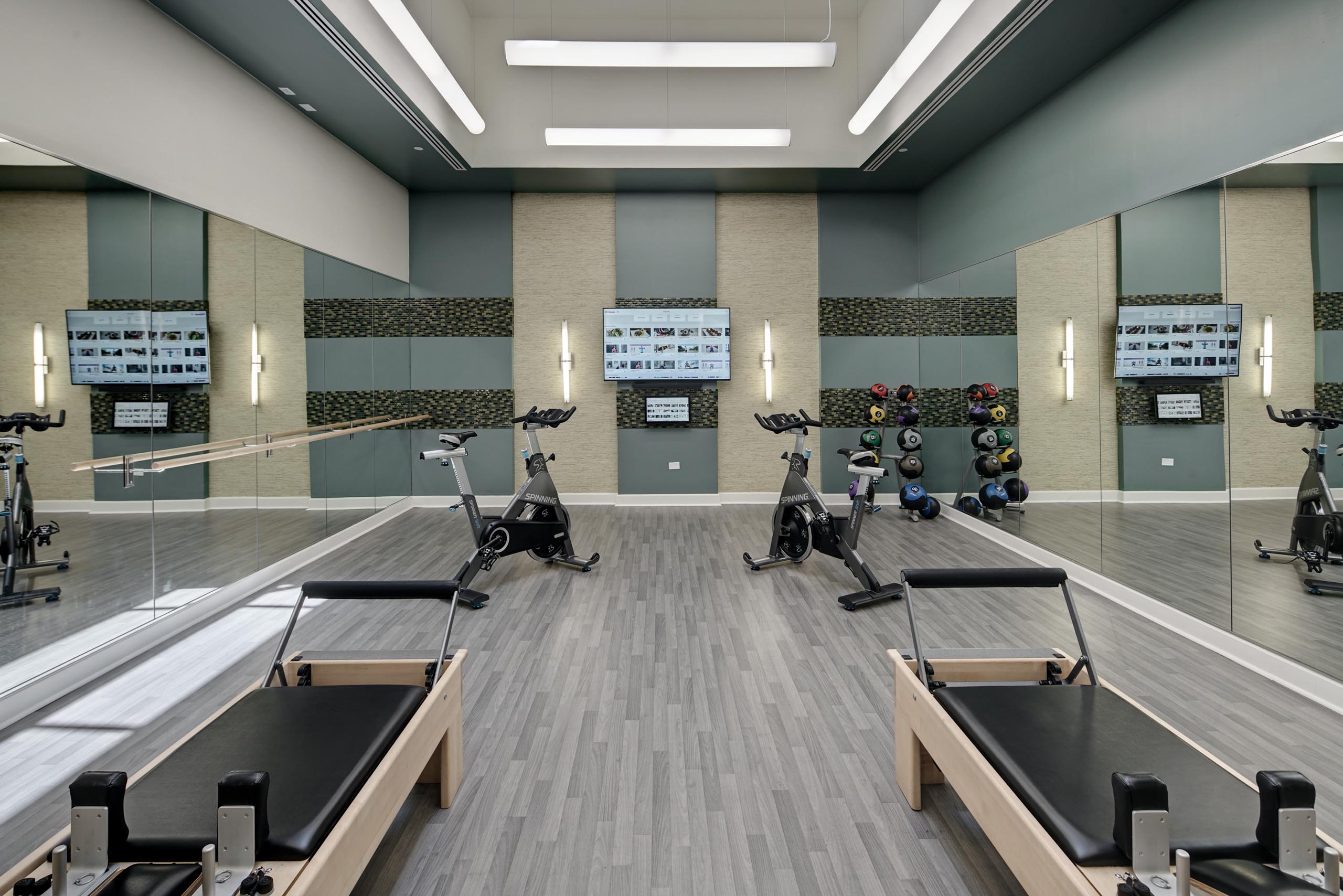 AMLI Evanston Pilates and spin studio with mirrored walls and grey flooring featuring spin bikes and reformers