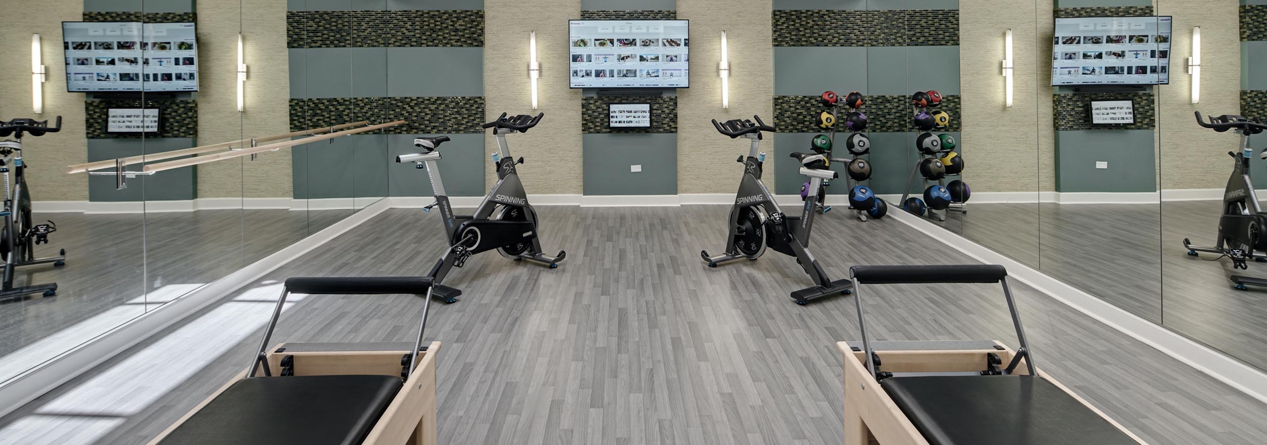 AMLI Evanston Pilates and spin studio with mirrored walls and grey flooring featuring spin bikes and reformers