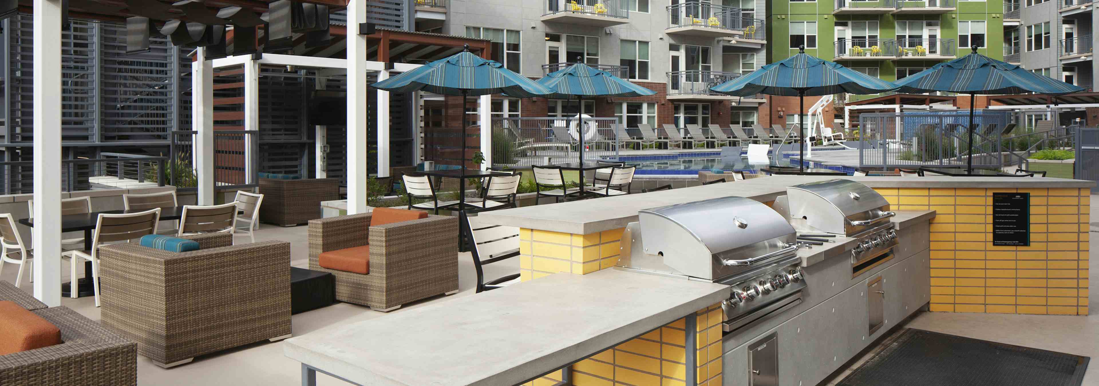 Poolside barbeque grills at AMLI Riverfront Green apartments with a cabana area with various comfortable chairs and tables