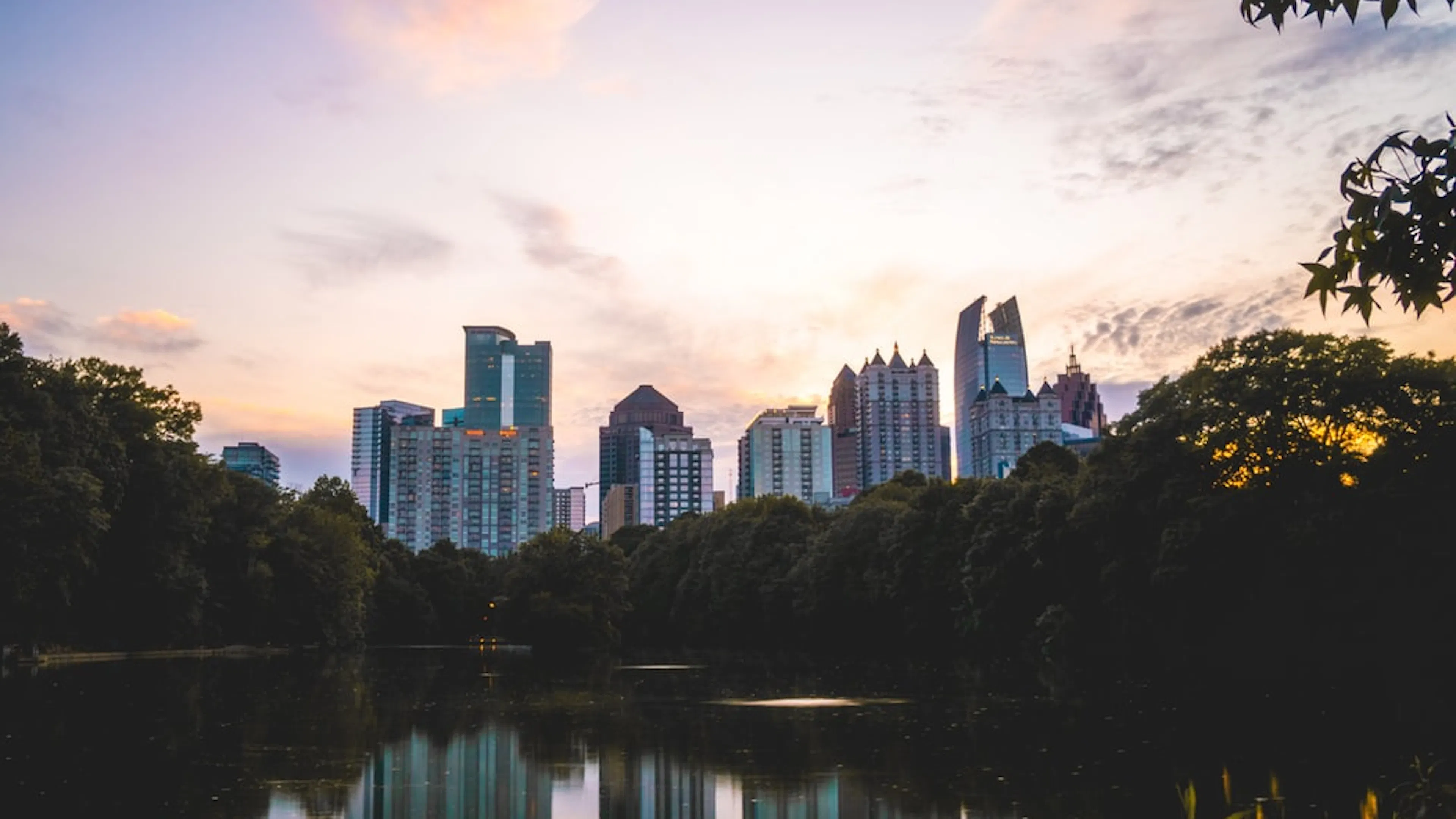 Tall skyscrapers in Downtown Atlanta reflected on a lake and surrounded by trees
