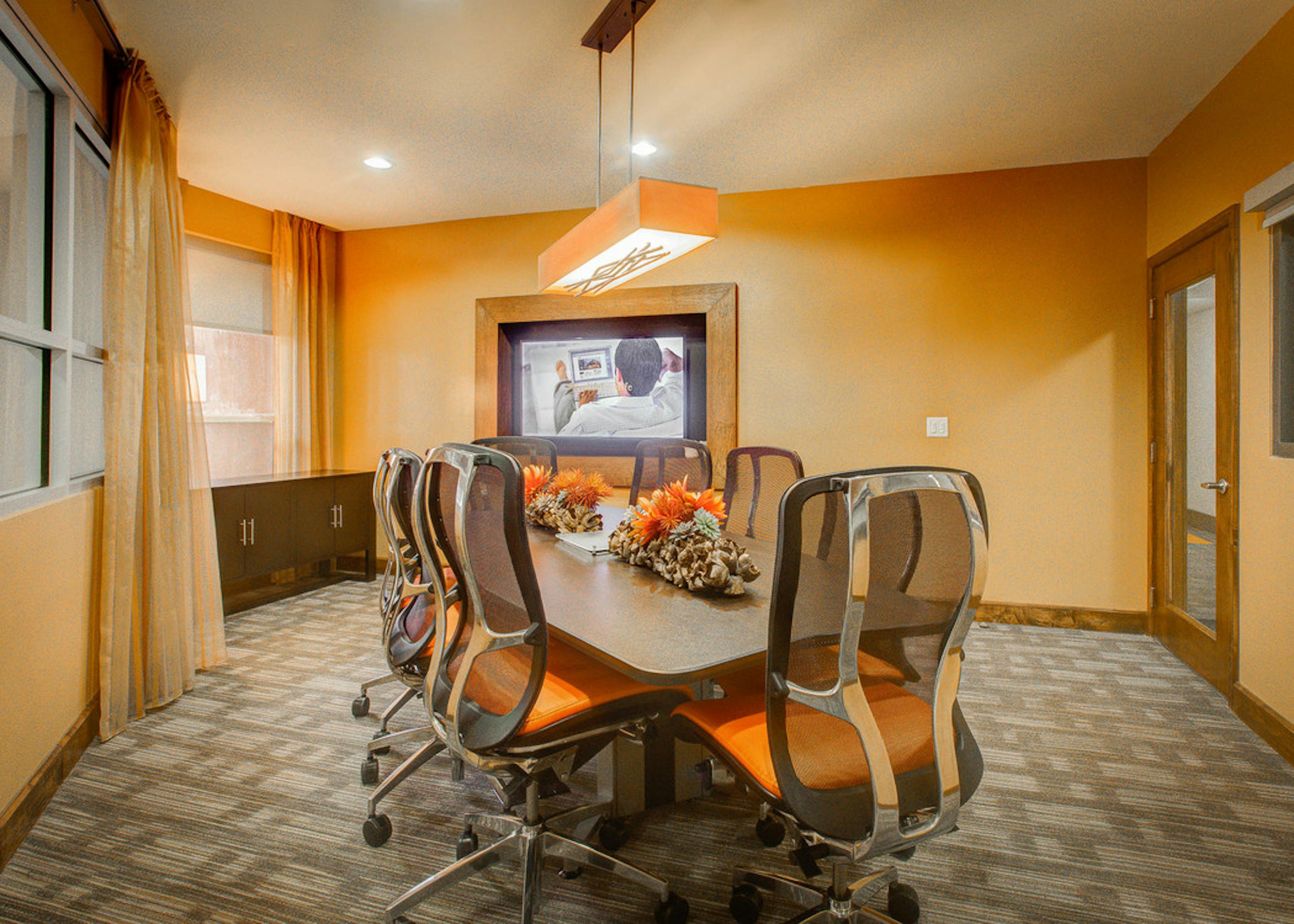 Interior view of a conference room at AMLI Riverfront Park apartments with a long table with rolling chairs and a television
