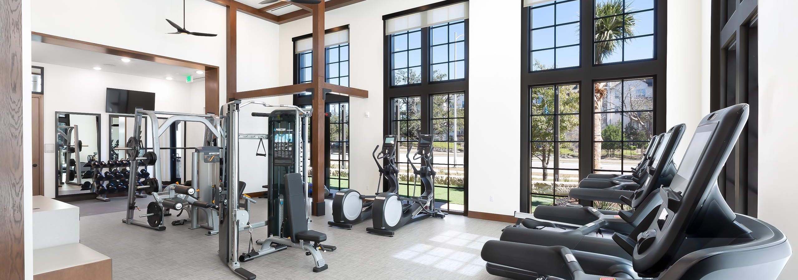 AMLI Lakeline apartment building fitness center with black large windows and cardio and weight training machines