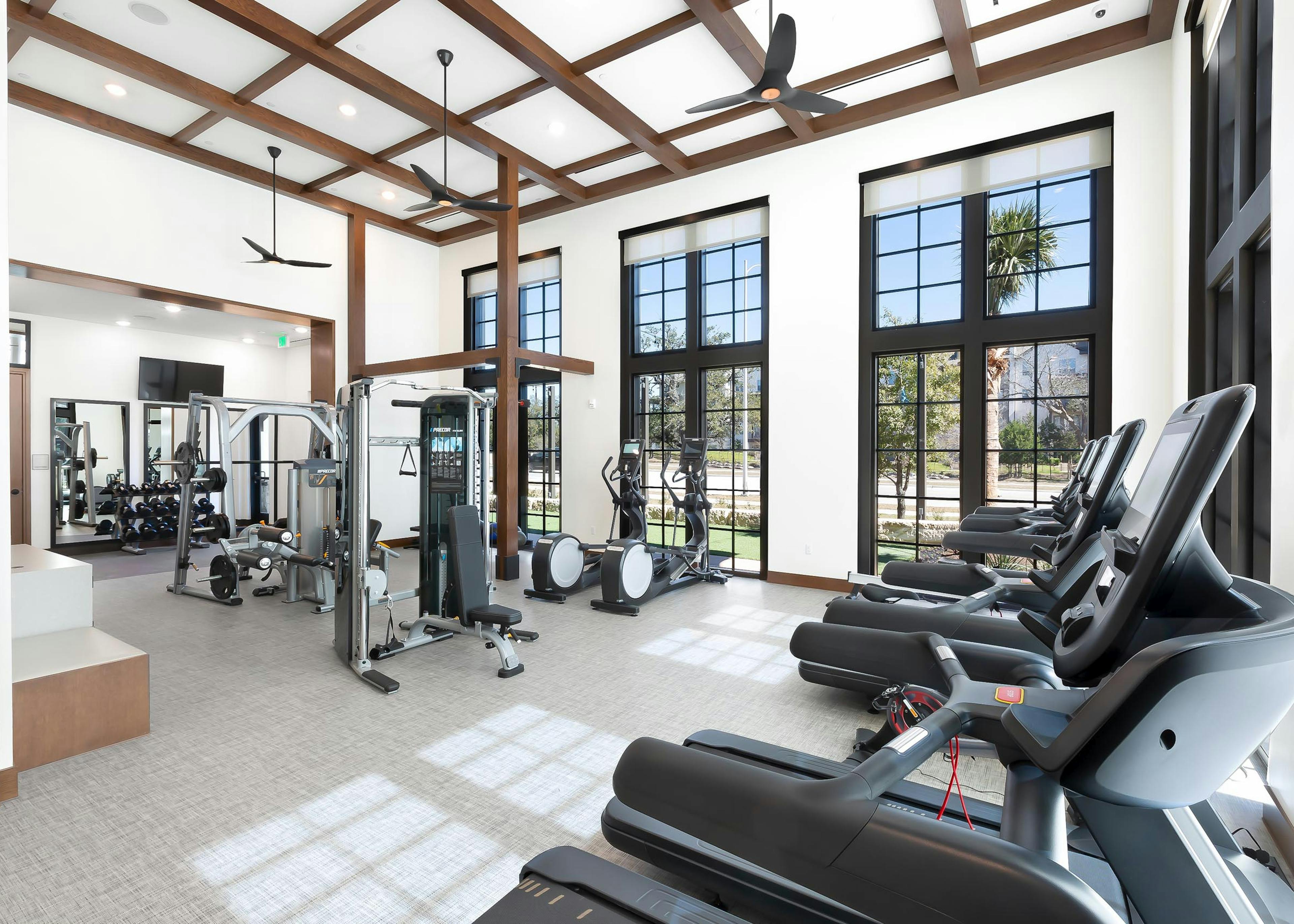 AMLI Lakeline apartment building fitness center with black large windows and cardio and weight training machines