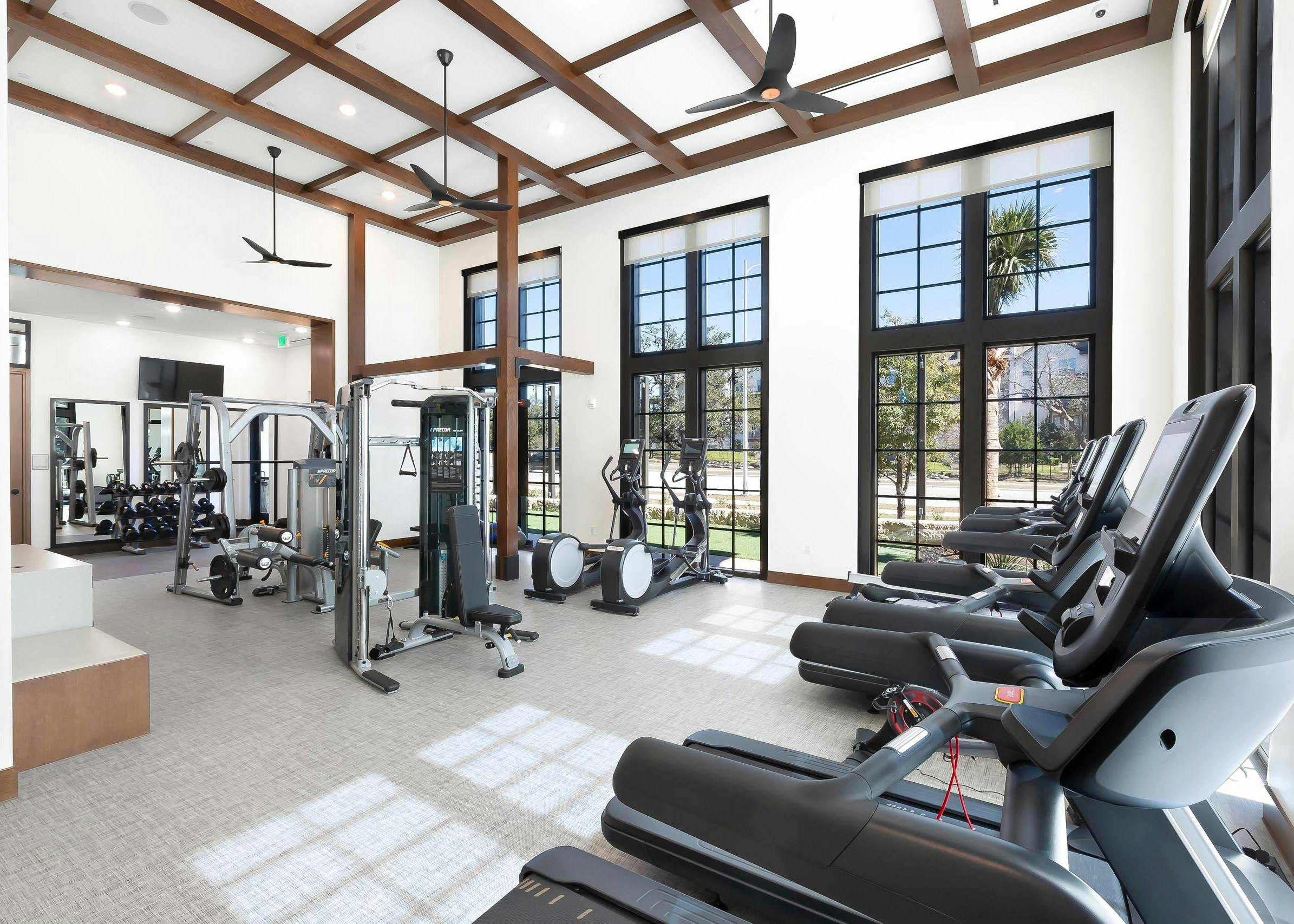 AMLI Lakeline apartment building fitness center with black large windows and cardio and weight training machines