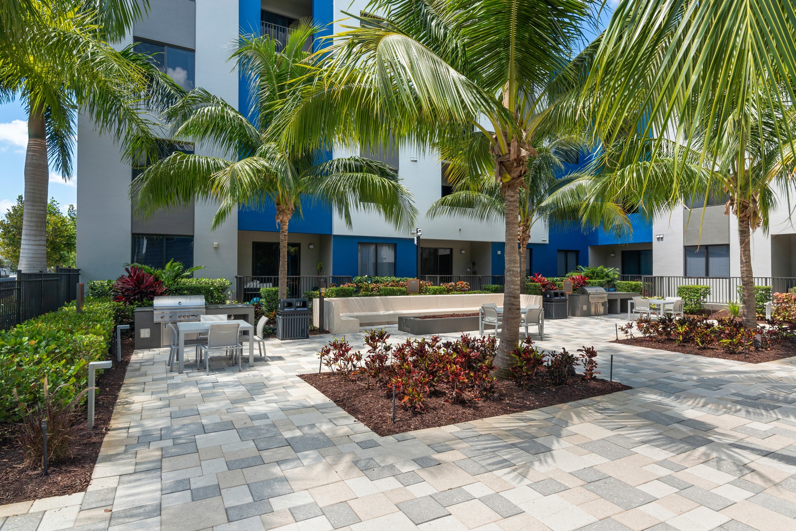 AMLI 8800 courtyard with steel grills and firepit with built in concrete bench and table and chairs and palm trees 