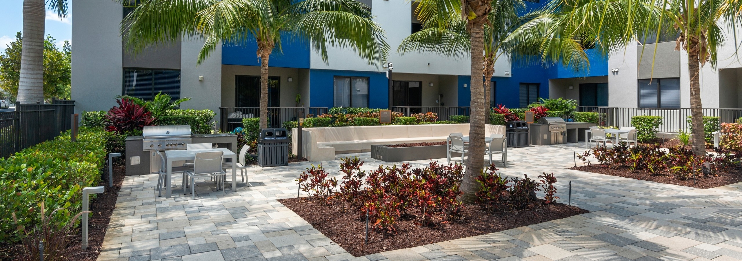 AMLI 8800 courtyard with steel grills and firepit with built in concrete bench and table and chairs and palm trees