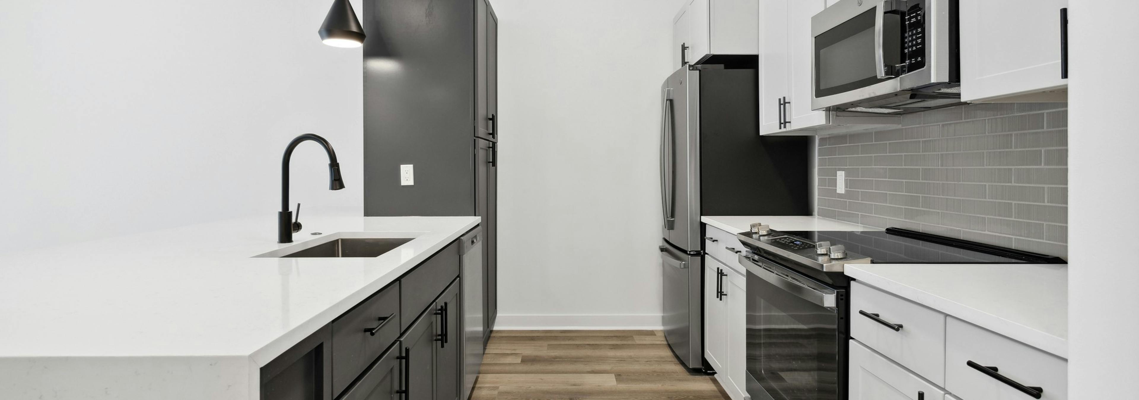 AMLI Old 4th Ward kitchen with white cabinets and white counter tops with stainless steel appliances and a black cabinet peninsula 