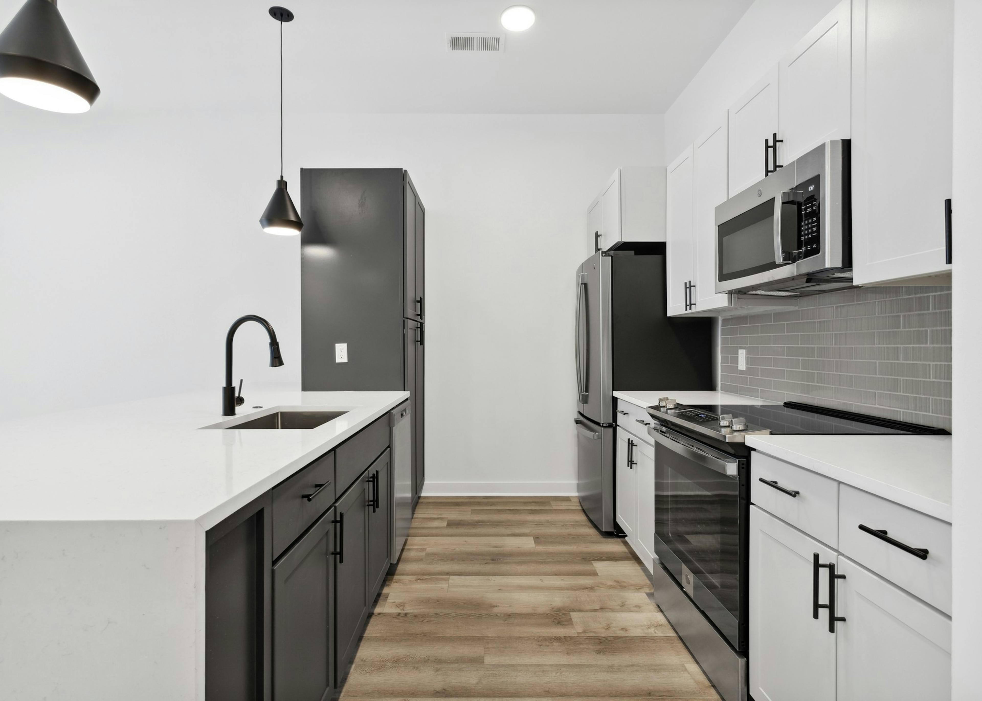 AMLI Old 4th Ward kitchen with white cabinets and white counter tops with stainless steel appliances and a black cabinet peninsula 