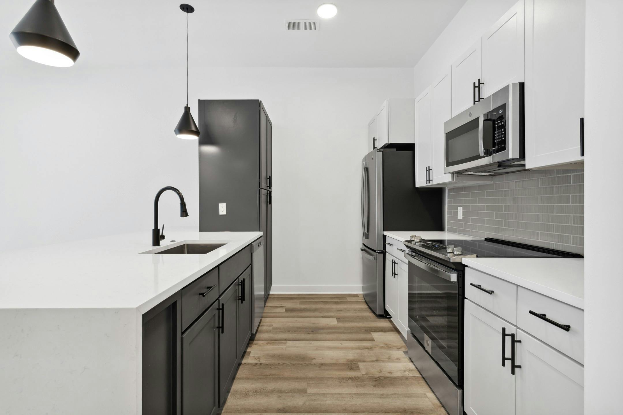 AMLI Old 4th Ward kitchen with white cabinets and white counter tops with stainless steel appliances and a black cabinet peninsula