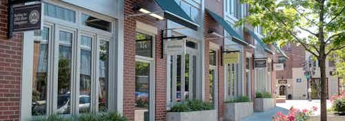 Exterior view of AMLI Evanston building with brick facade and retail shops along the ground level across vibrant green plants
