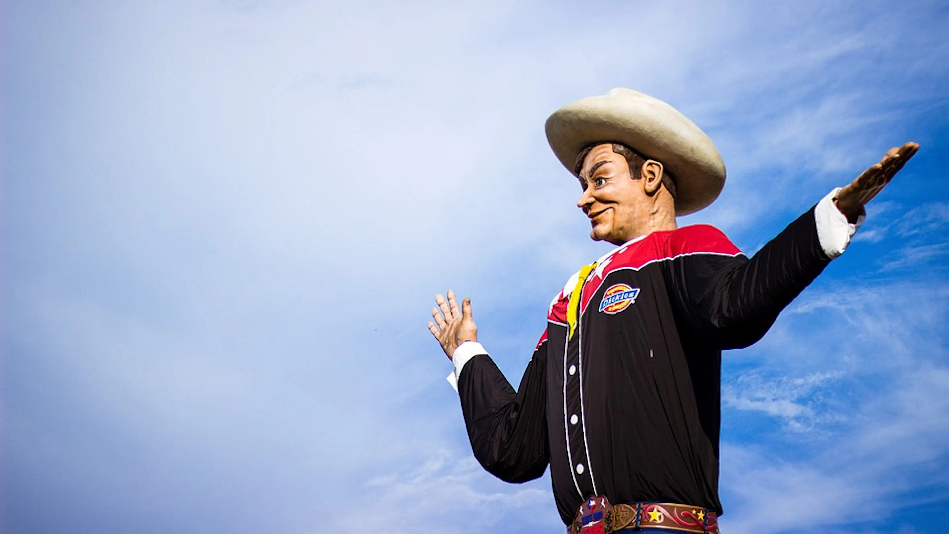 The Big Tex cowboy statue dressed in a cowboy shirt and cowboy hat set against a blue sky