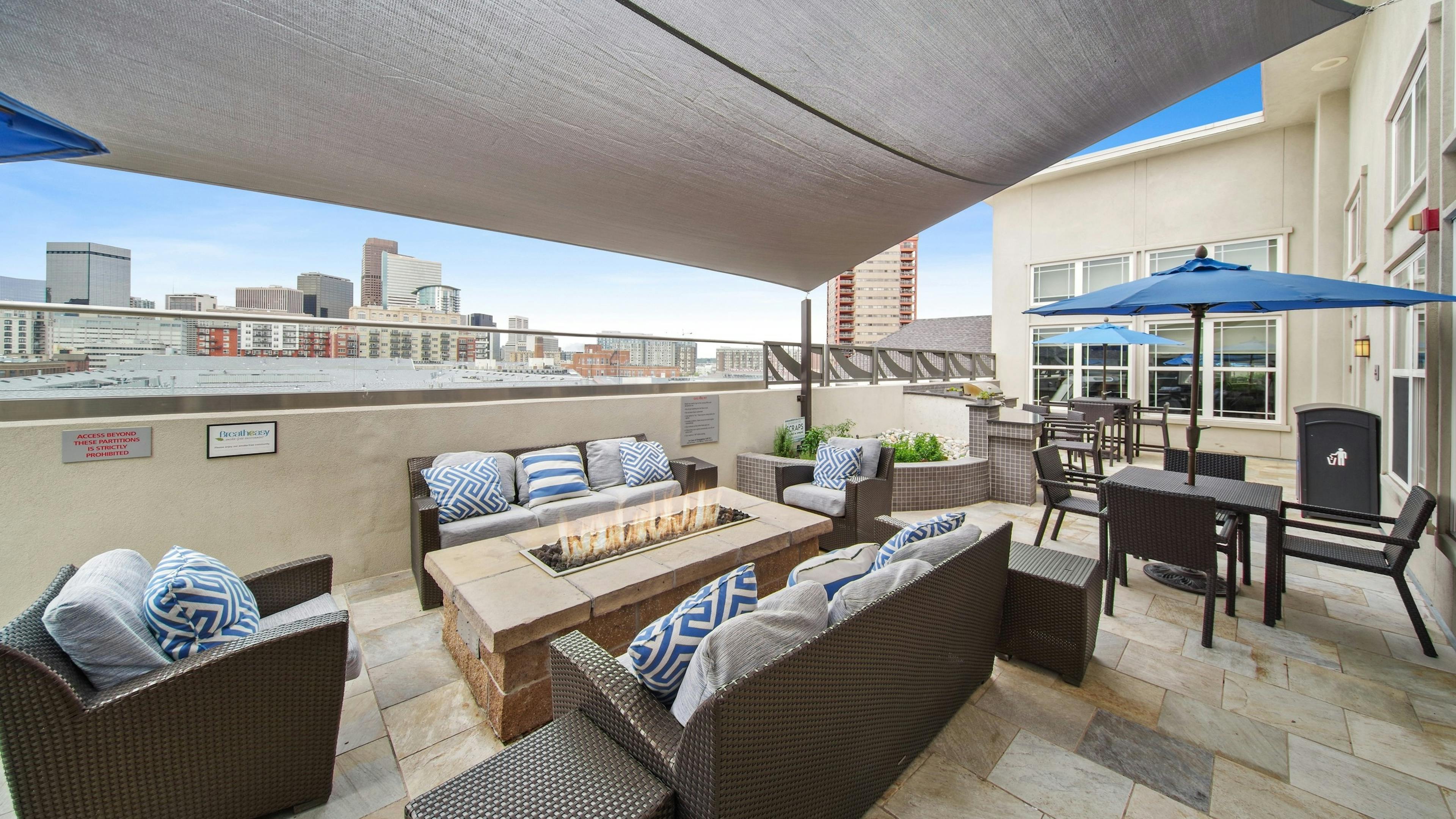 Rooftop lounge at AMLI Park Avenue with several seating areas and a fire pit and a large canopy and city skyline view