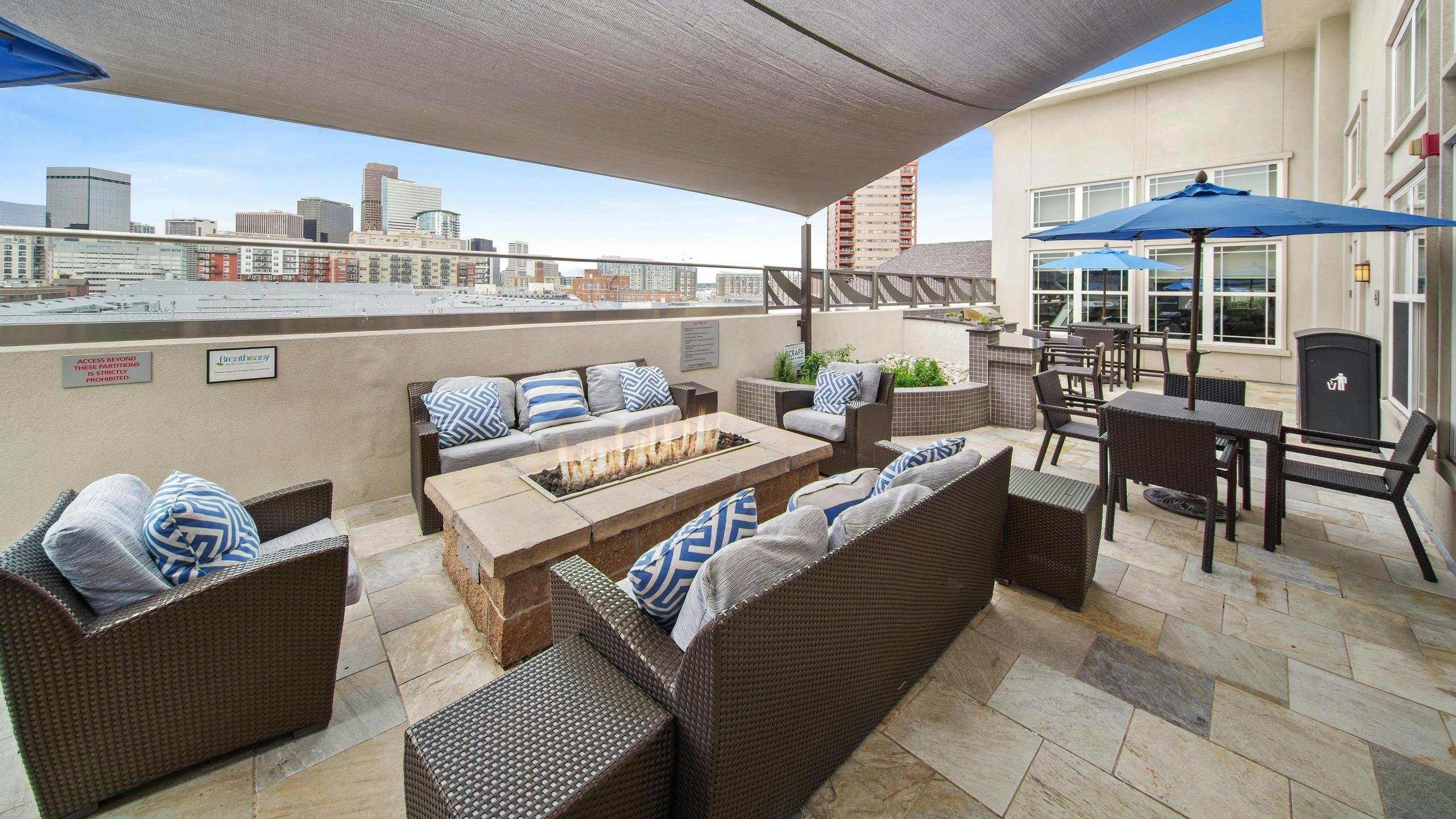 Rooftop lounge at AMLI Park Avenue with several seating areas and a fire pit and a large canopy and city skyline view