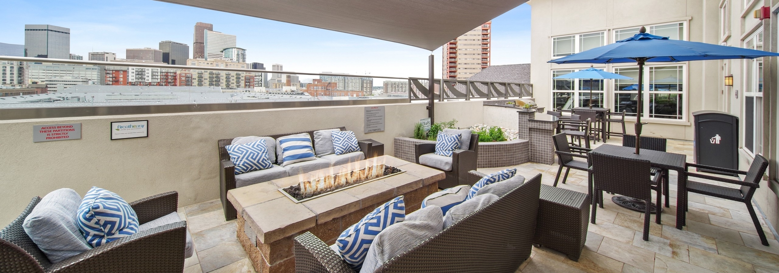 Rooftop lounge at AMLI Park Avenue with several seating areas and a fire pit and a large canopy and city skyline view