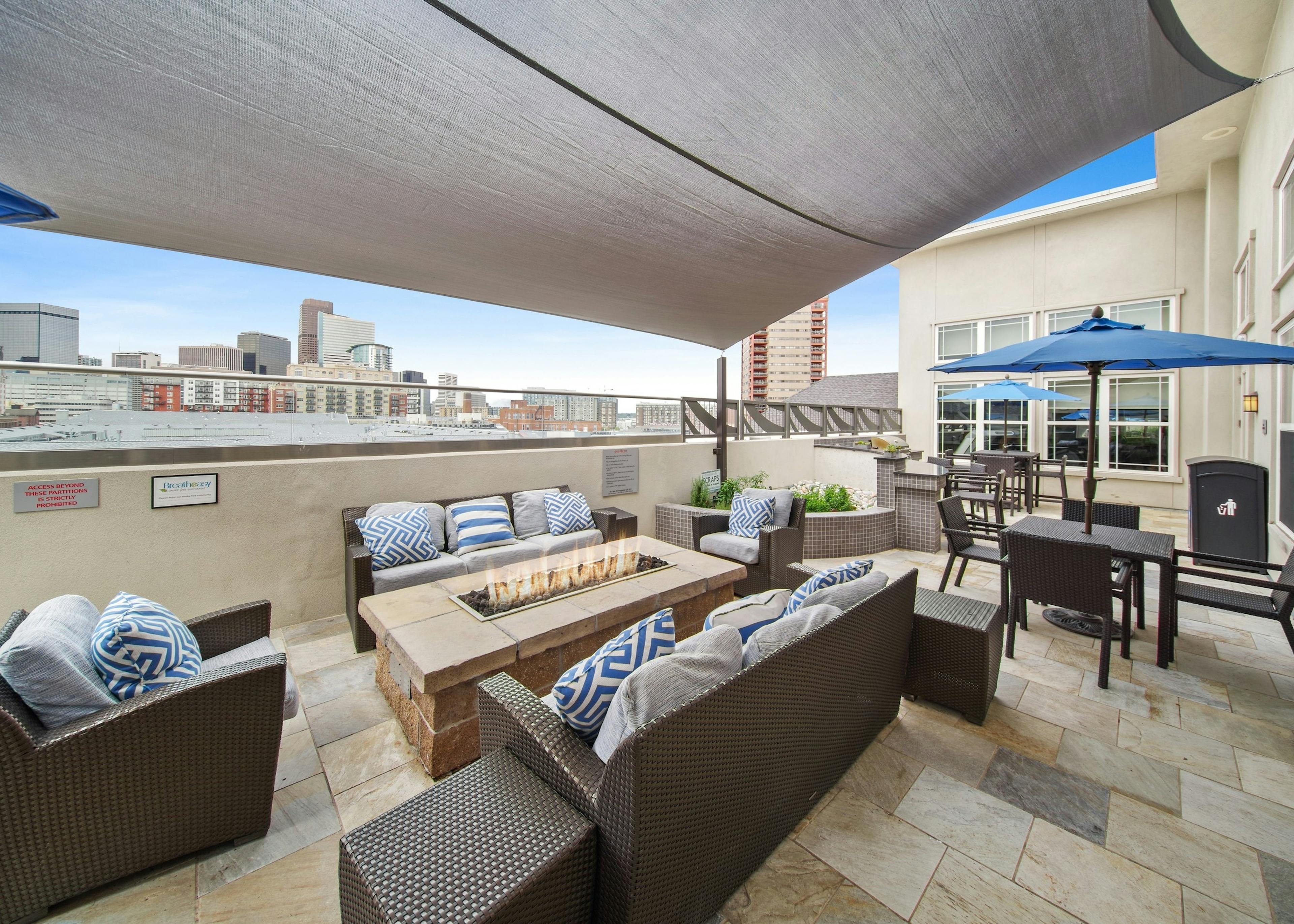 Rooftop lounge at AMLI Park Avenue with several seating areas and a fire pit and a large canopy and city skyline view