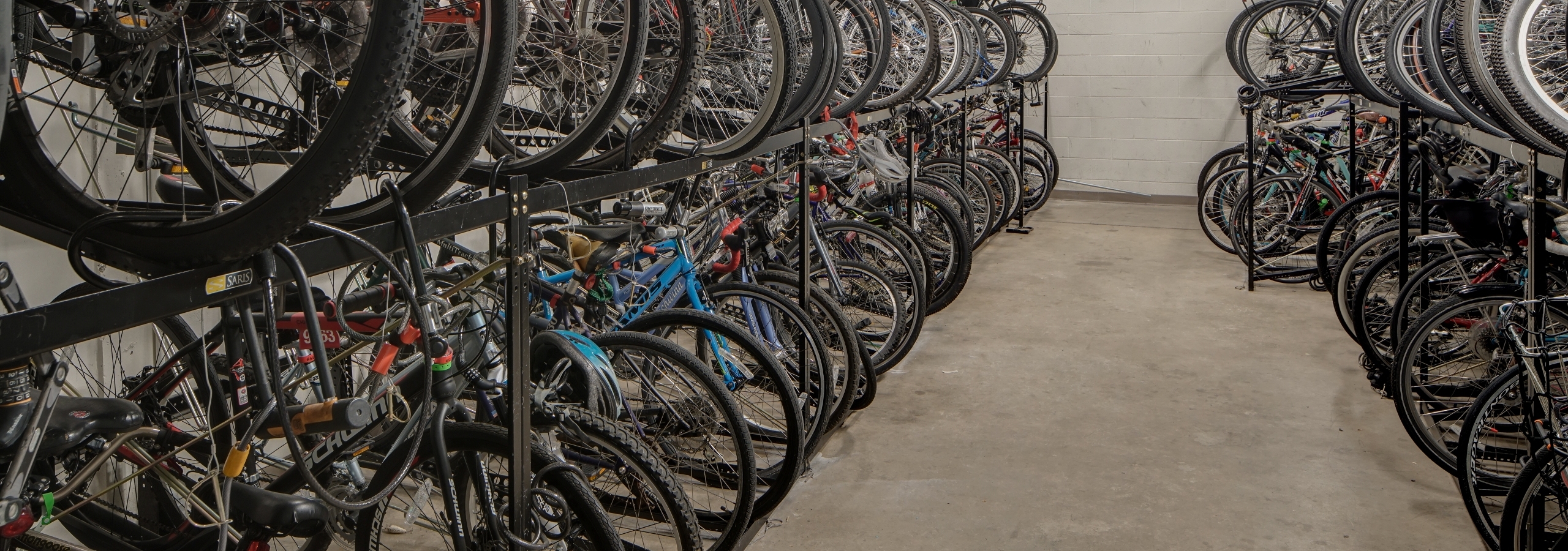 Interior view of roughly fifty resident bicycles in a well lit storage area with cement flooring and white walls at AMLI 900
