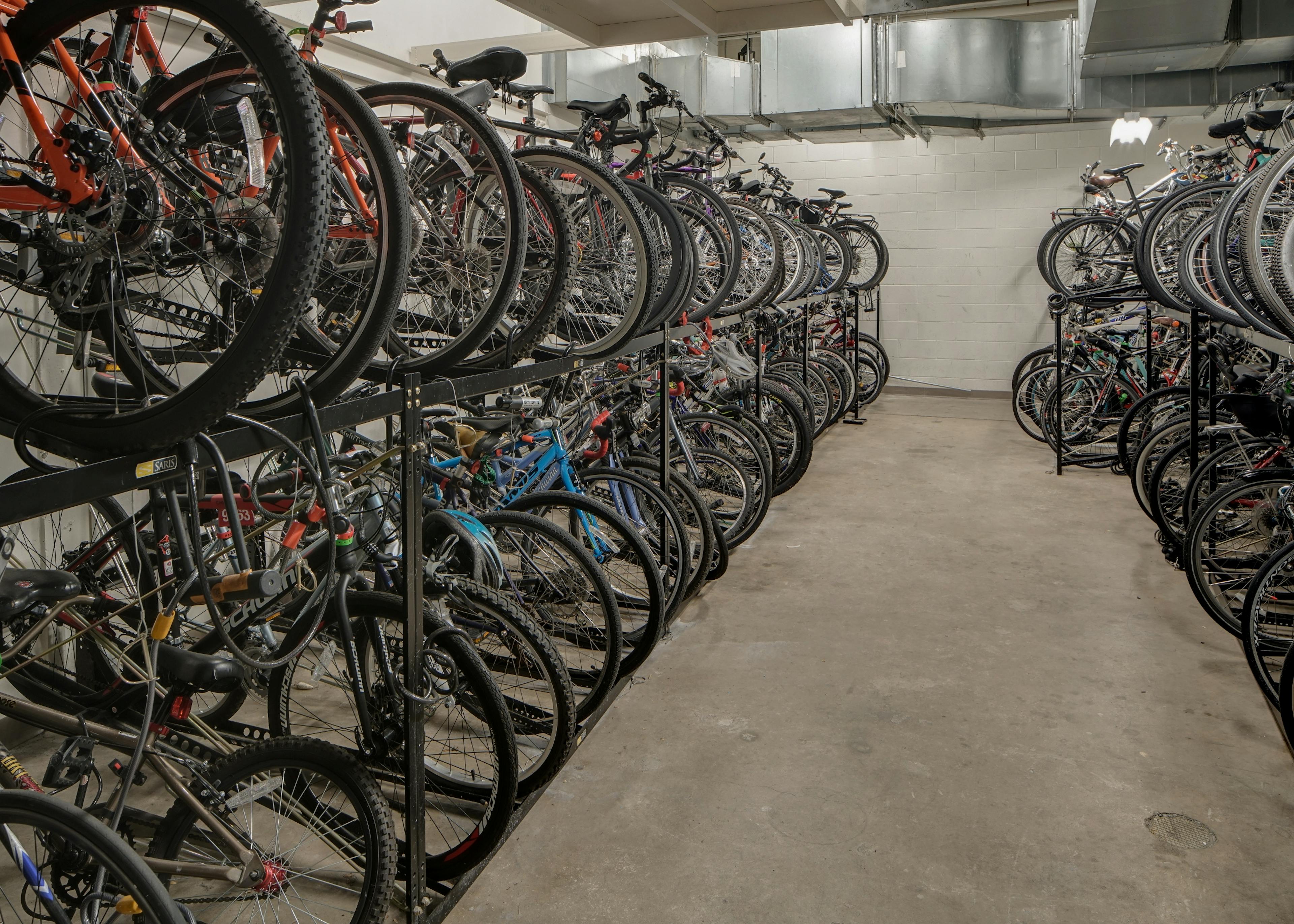 Interior view of roughly fifty resident bicycles in a well lit storage area with cement flooring and white walls at AMLI 900 