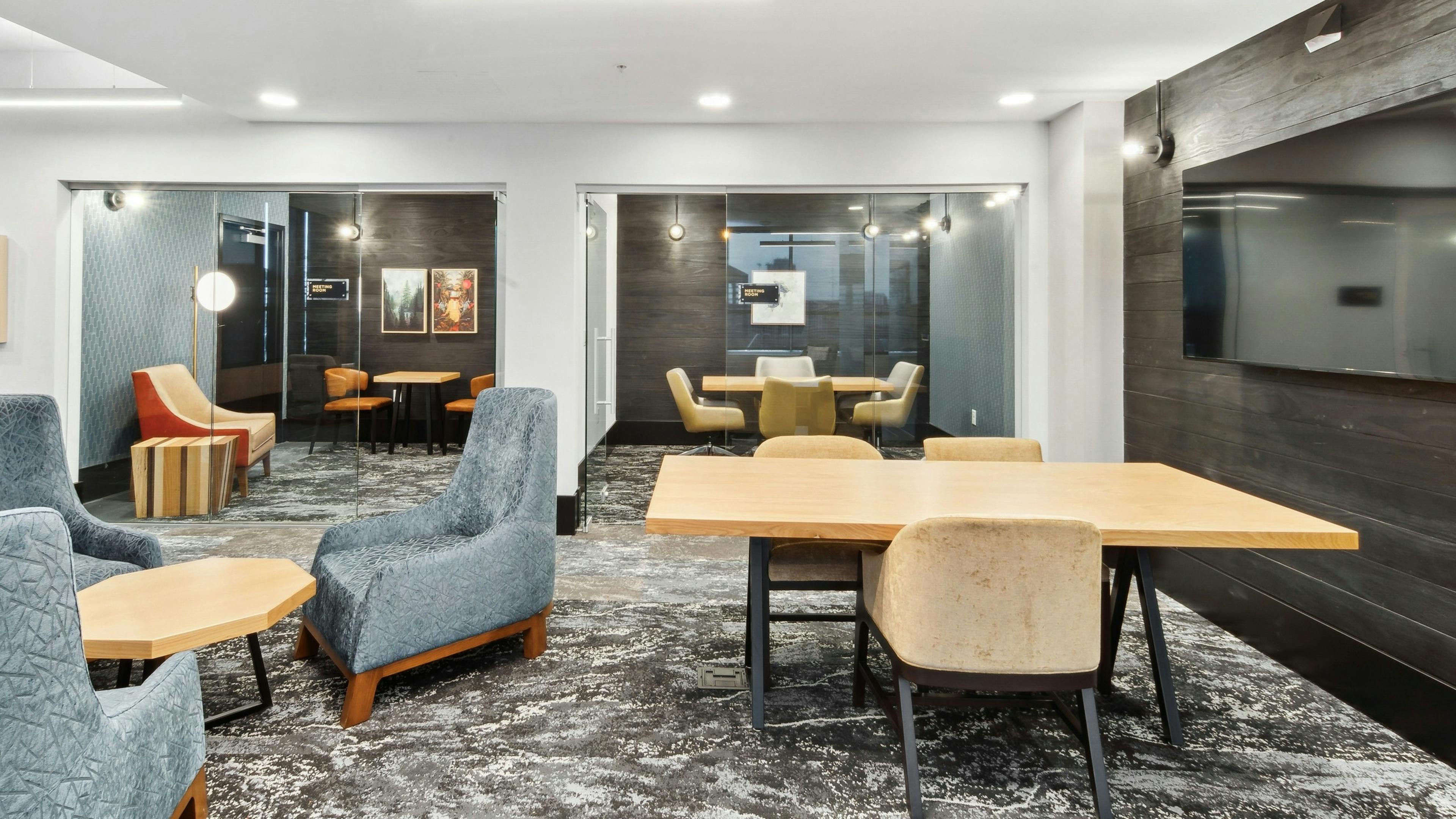 Interior view of a business center at AMLI RiNo with conference tables and plush chairs and 2 glass wall meeting rooms